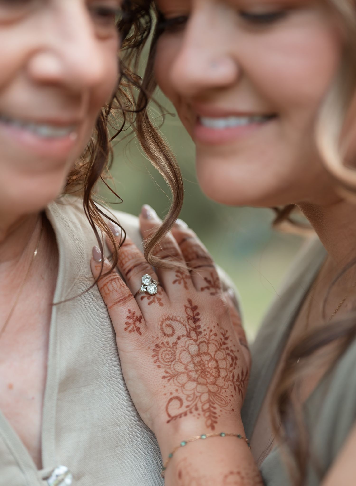 Intricate henna designs decorate hands against a light colored background.