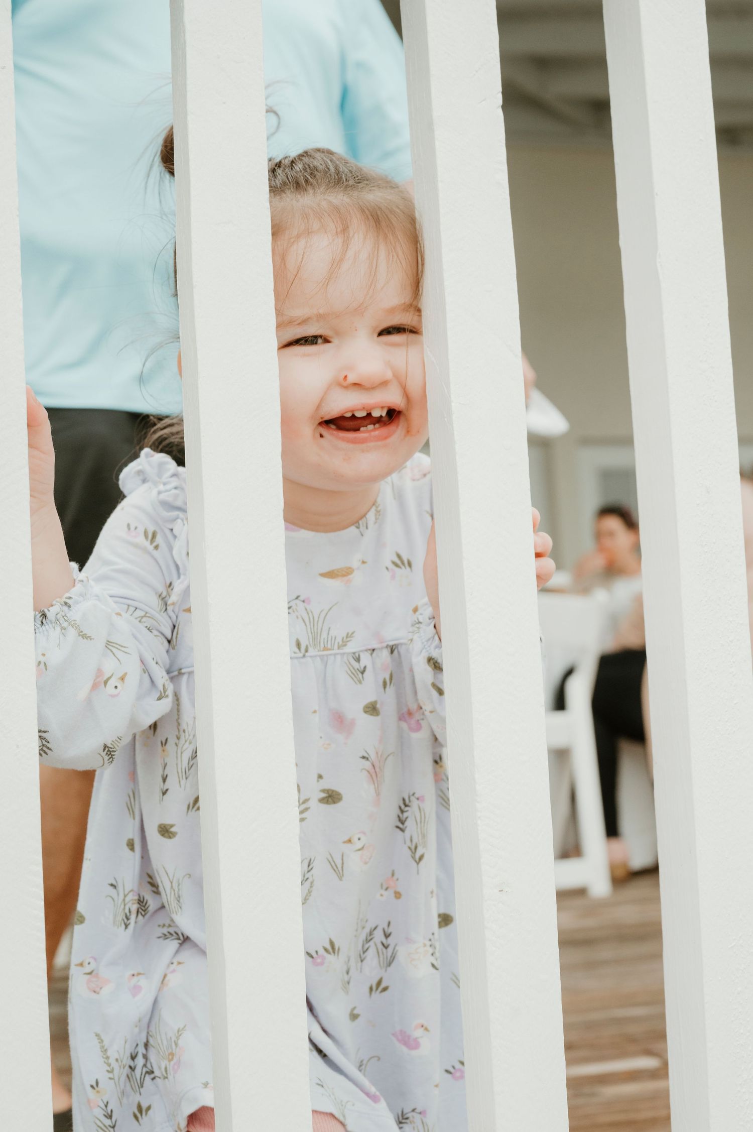 Joyful child laughing between white porch railings.