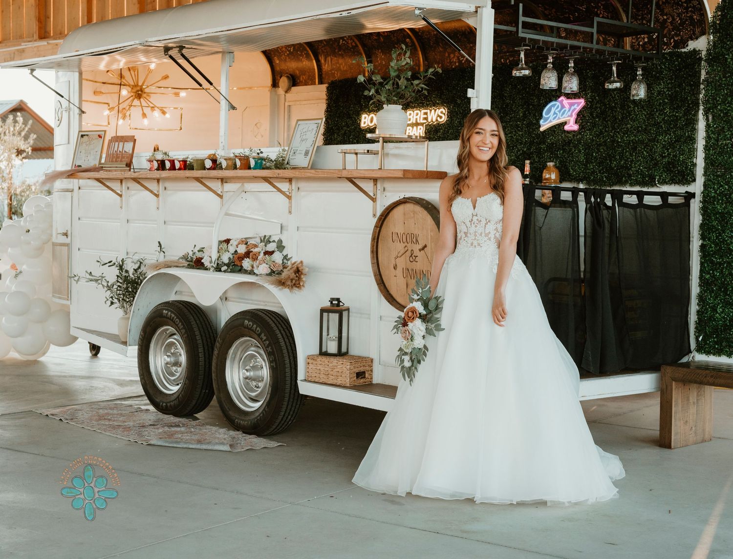 Decorated mobile bar trailer with rustic white finish and wine barrel accent.