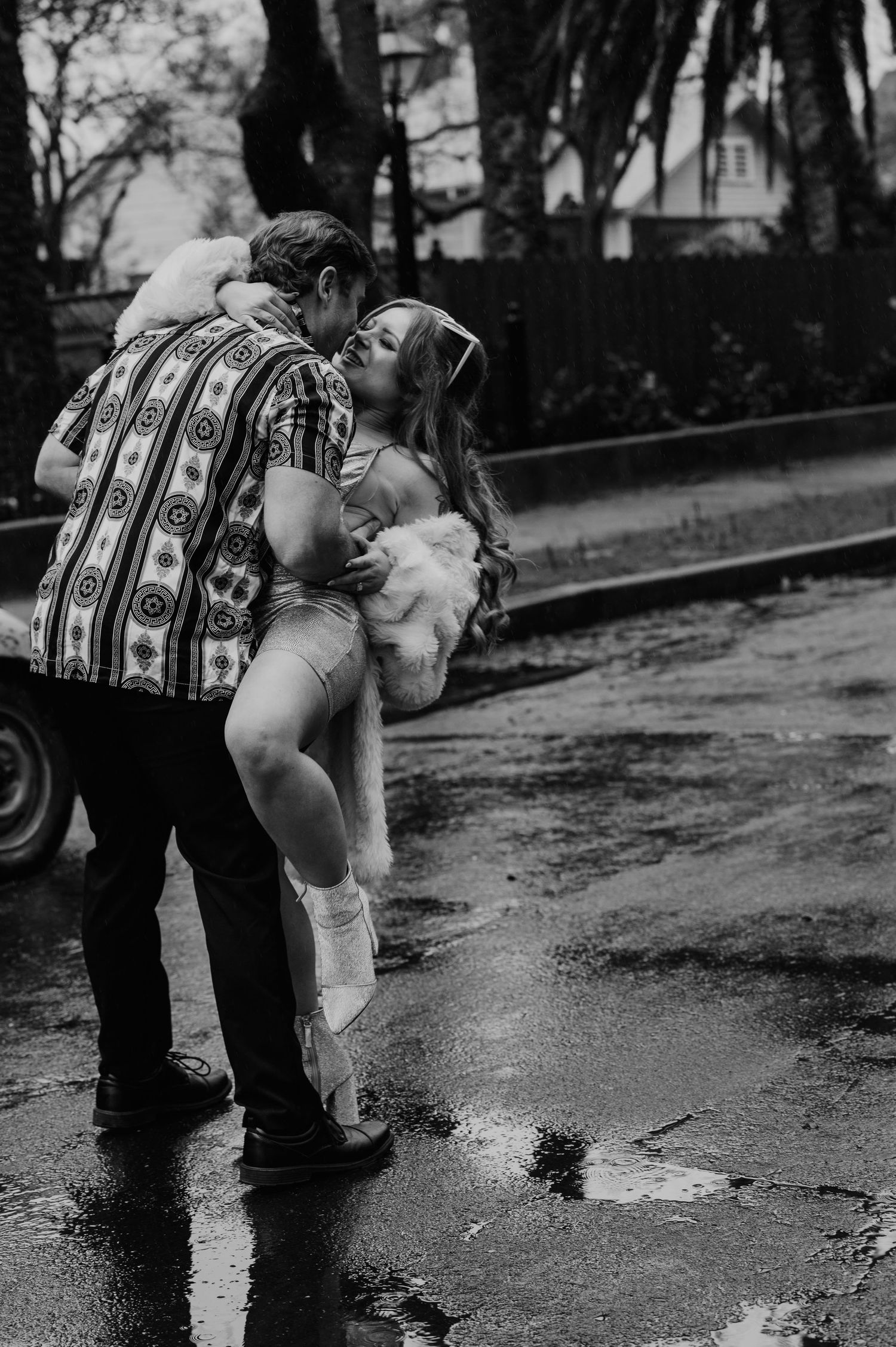 A black and white photo sequence shows someone bending down to examine a puddle of water on a wet path.