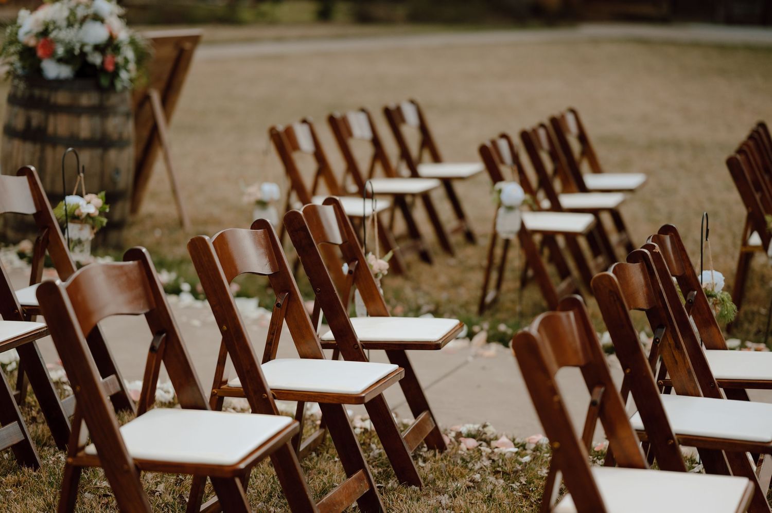 Brown wooden folding chairs arranged in rows for outdoor wedding ceremony.