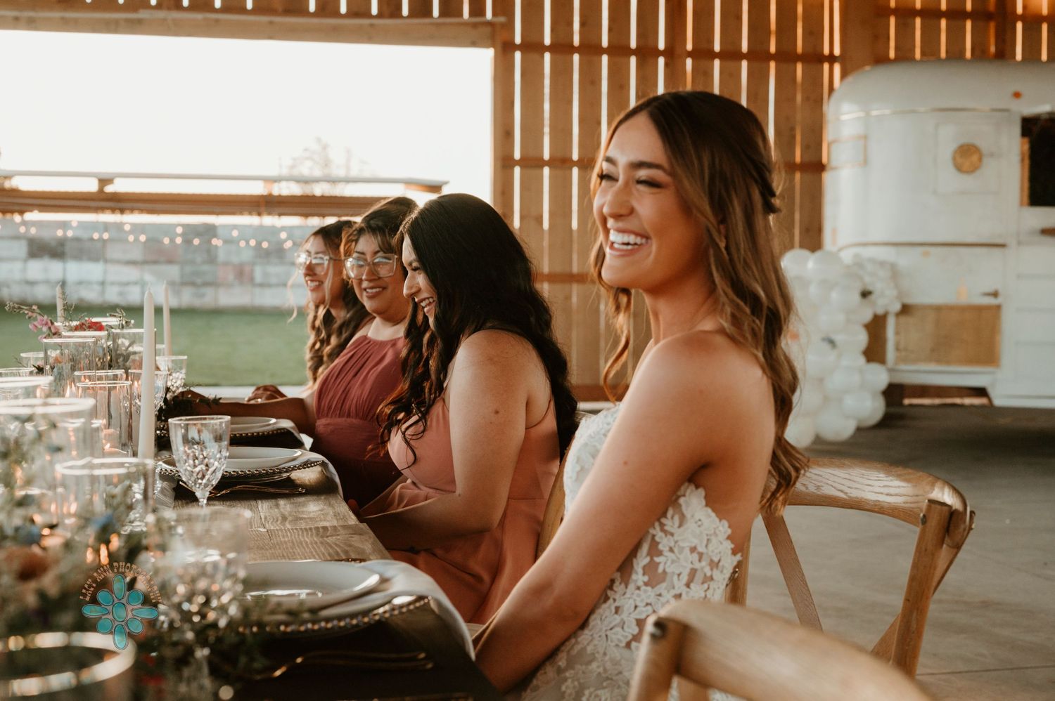 Wedding reception scene with guests seated at a rustic wooden table.