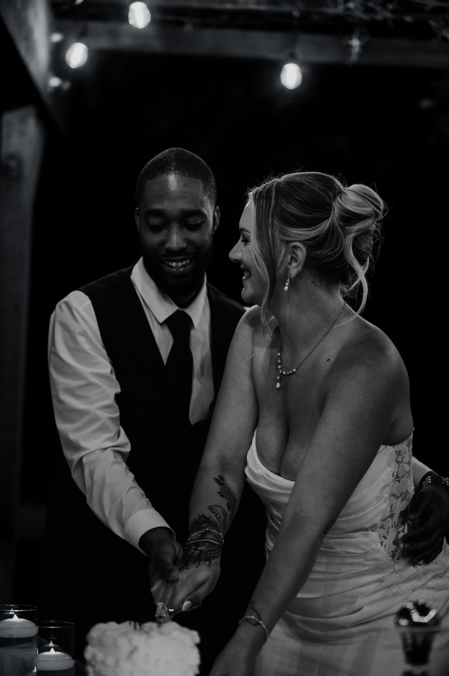 Candid reception moments captured in black and white as couple dances together.