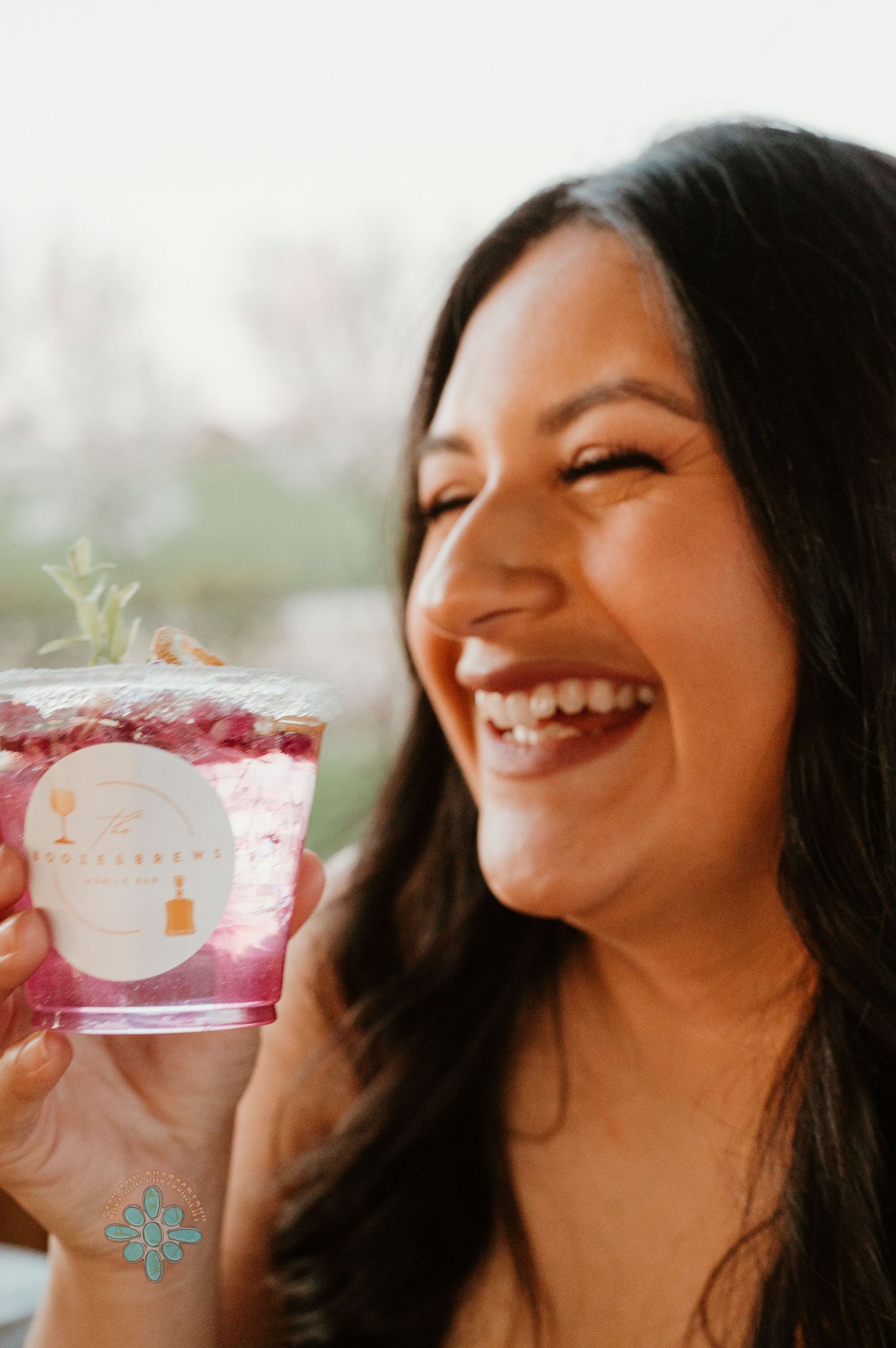 Person enjoying a pink beverage with garnish while smiling.