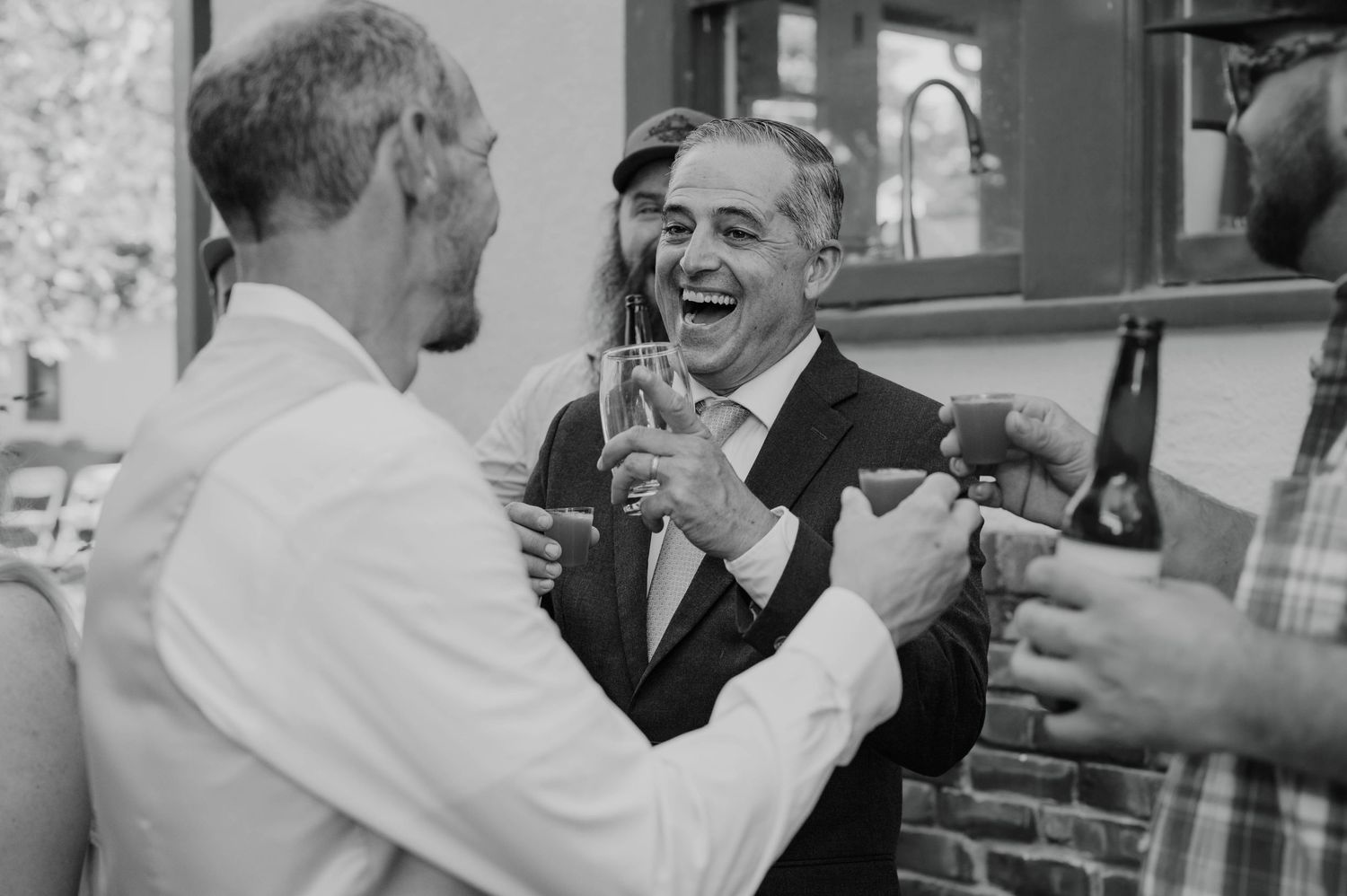 Guests sharing drinks and laughter at a celebratory gathering.