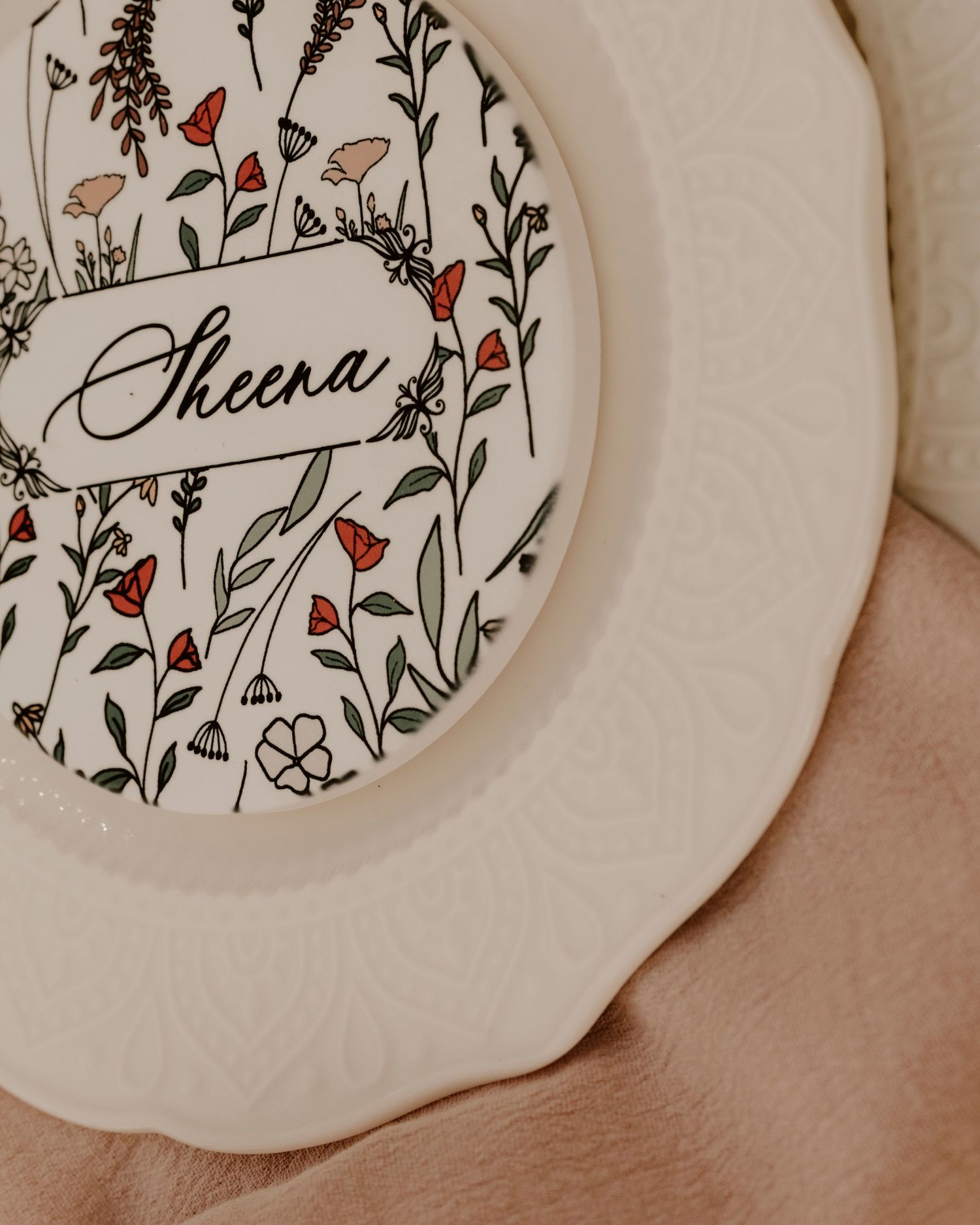 A decorative plate with delicate floral designs and the name 'Sheena' in elegant script.