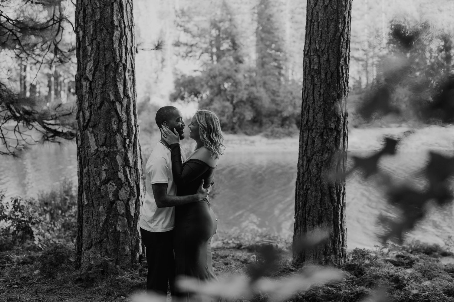 Black and white forest portrait session with pine trees creating natural framing.