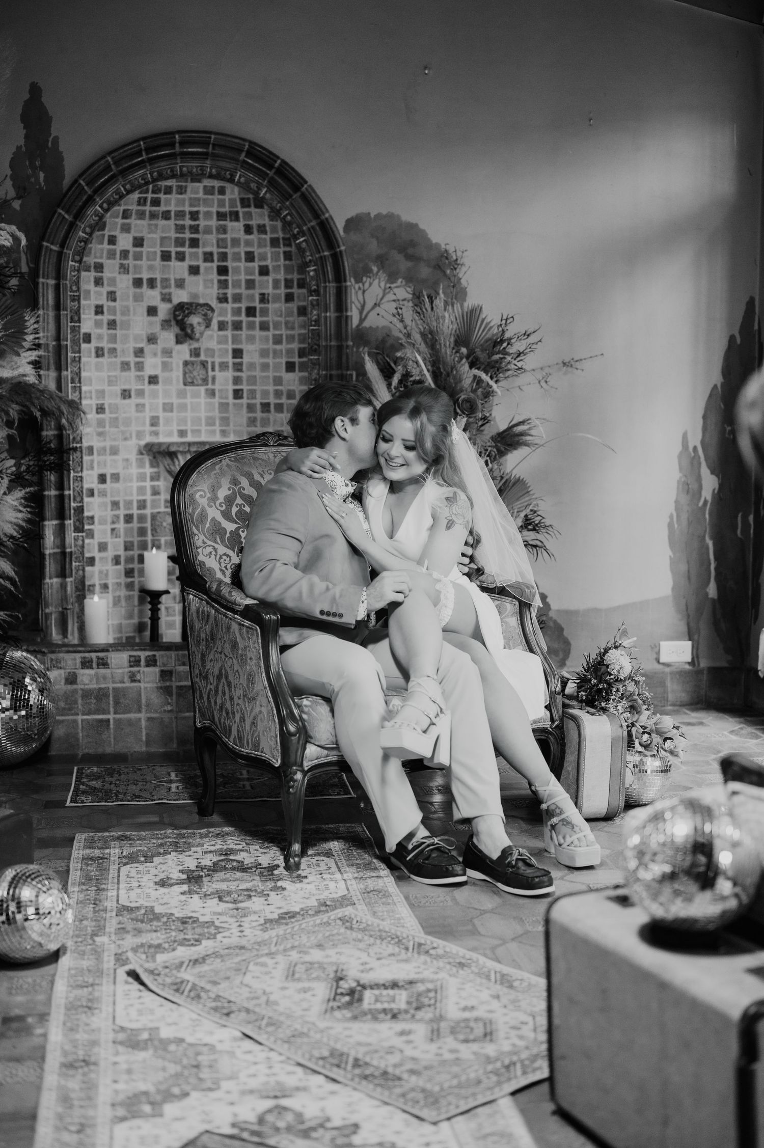 Black and white photograph of a casual indoor gathering with vintage-style furniture and decor.