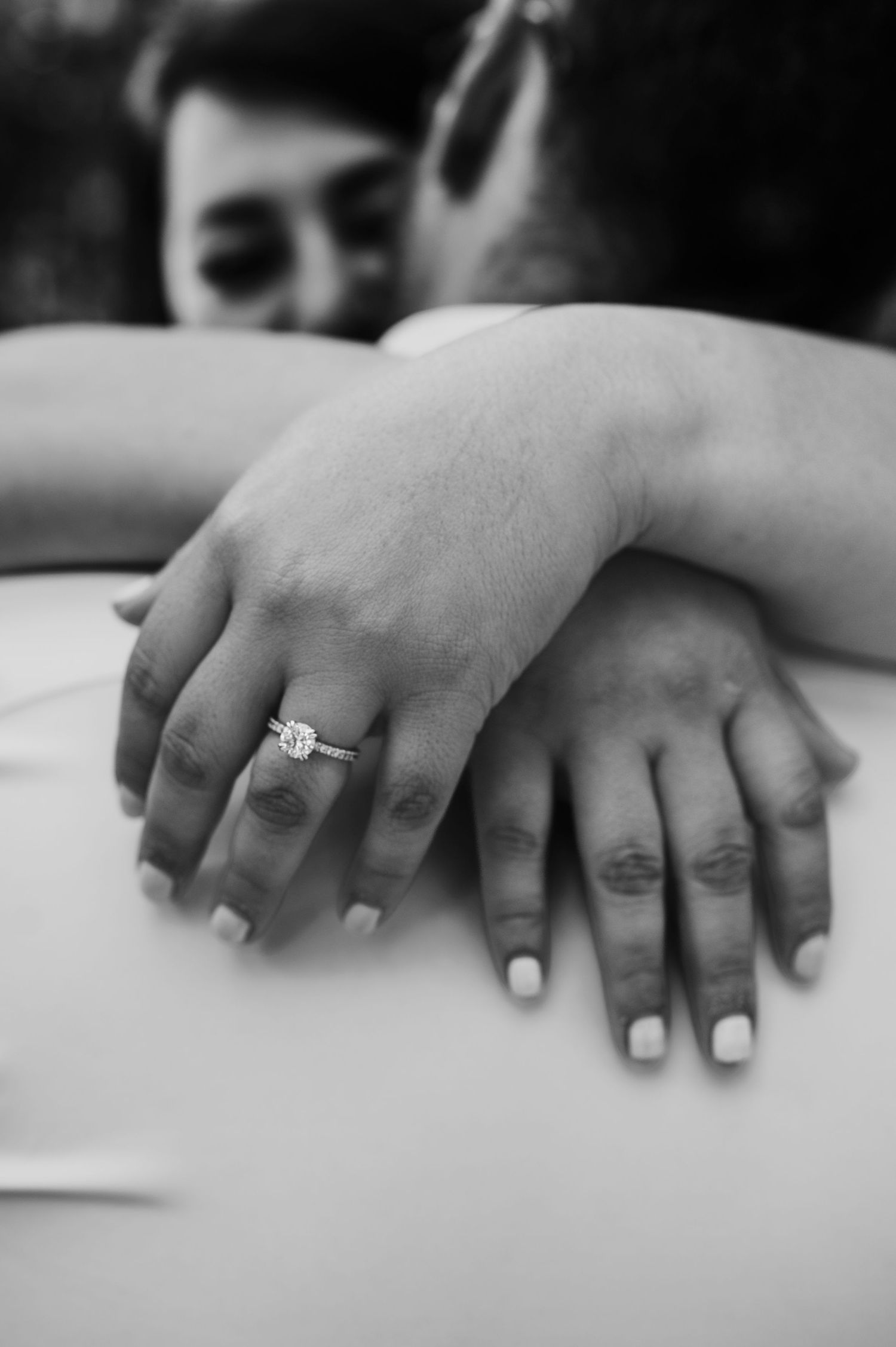 Close-up black and white photo of hands with an engagement ring.