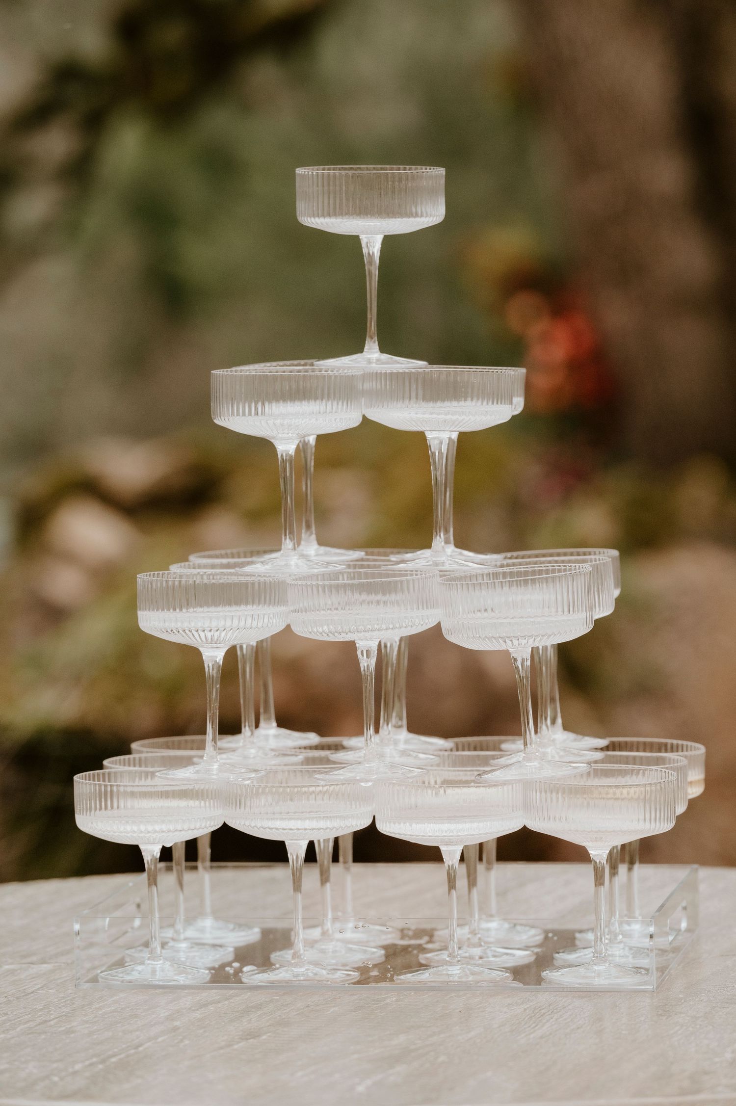 Elegant tower of empty champagne coupes arranged in wedding reception display.