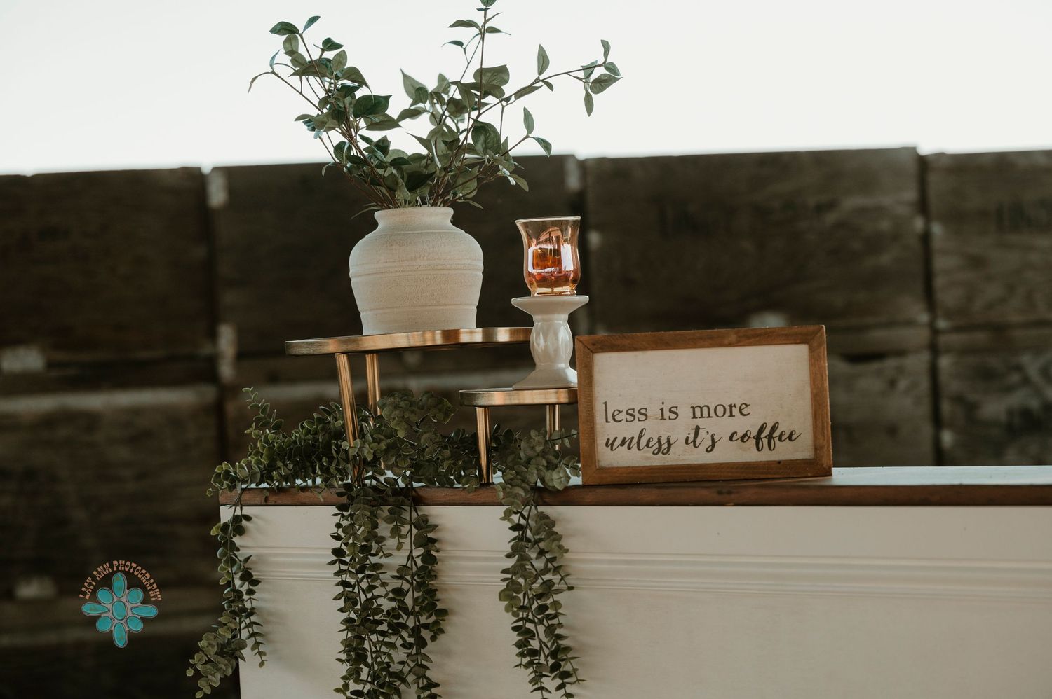 Rustic wedding decor featuring a white vase and wooden frame on dark backdrop.