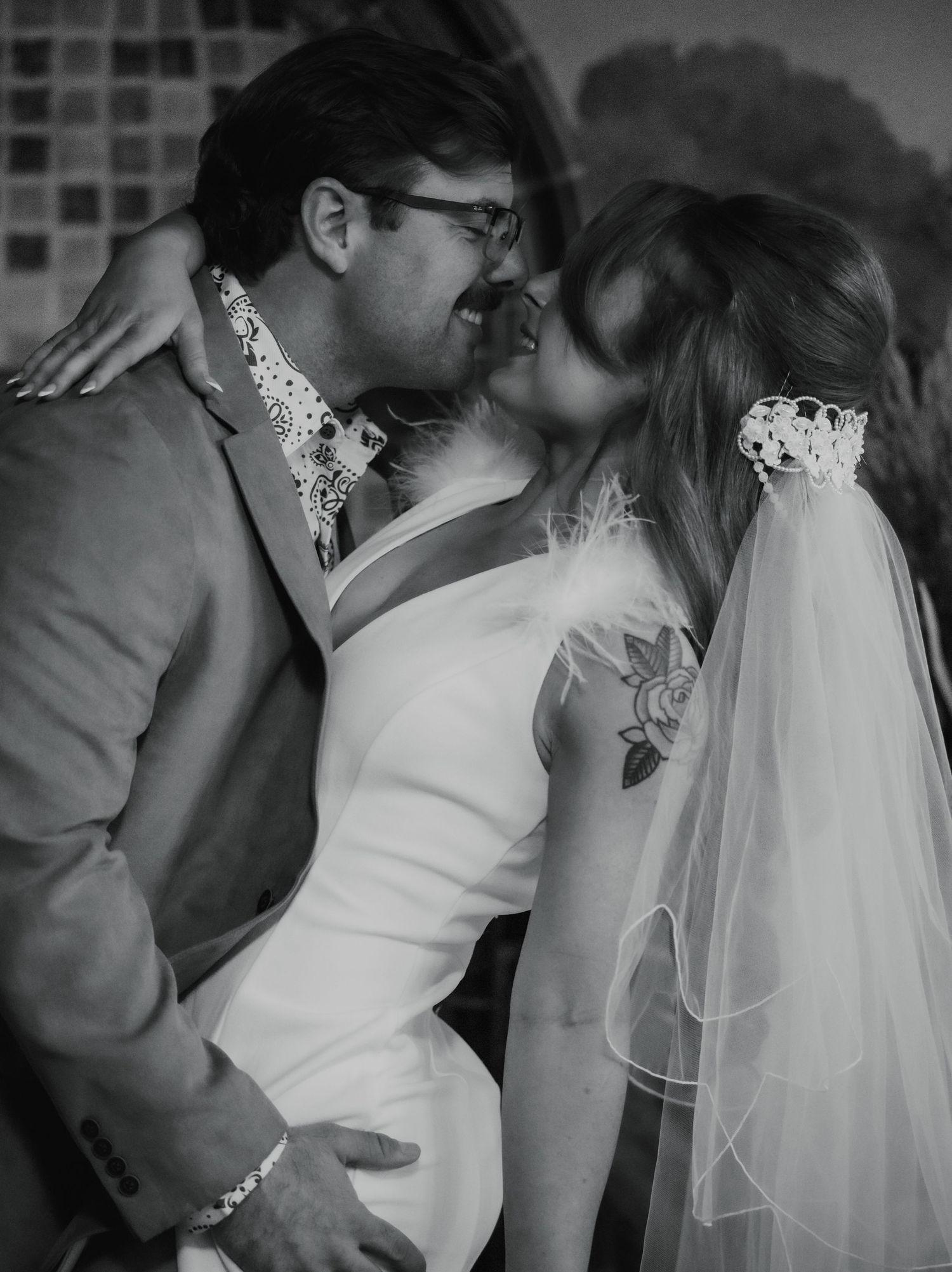Black and white photo of newlyweds sharing an intimate moment at their wedding celebration.