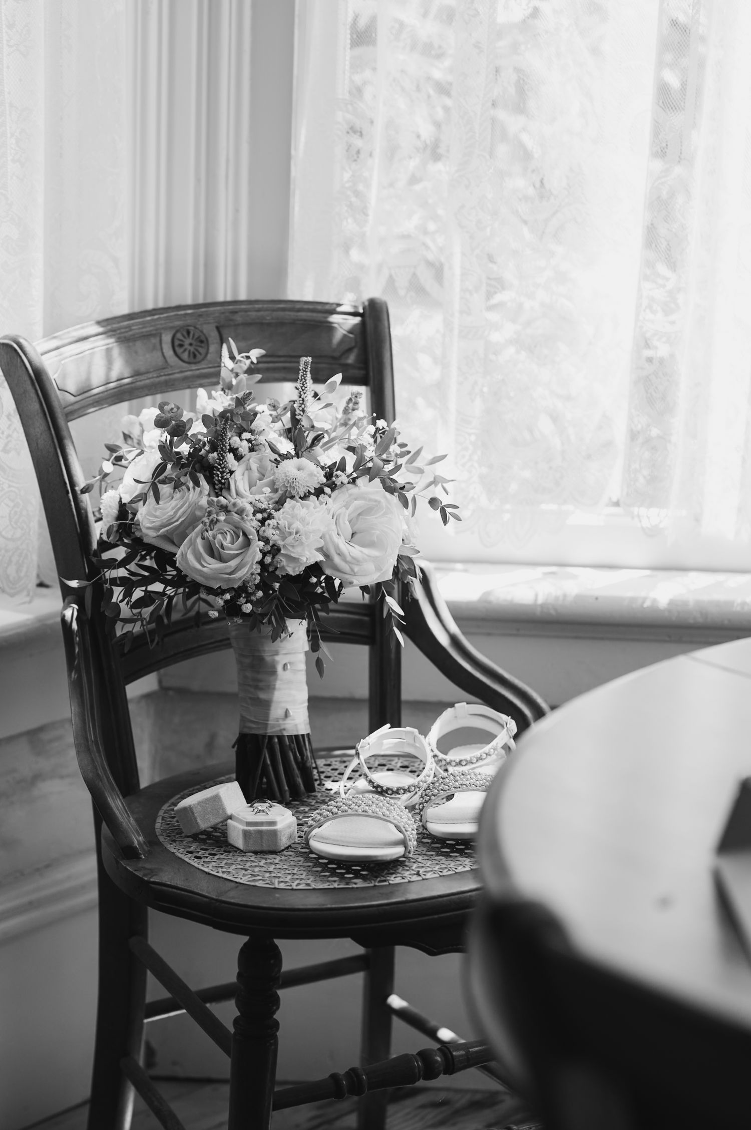 Black and white photo of elegant floral arrangements on antique chairs.