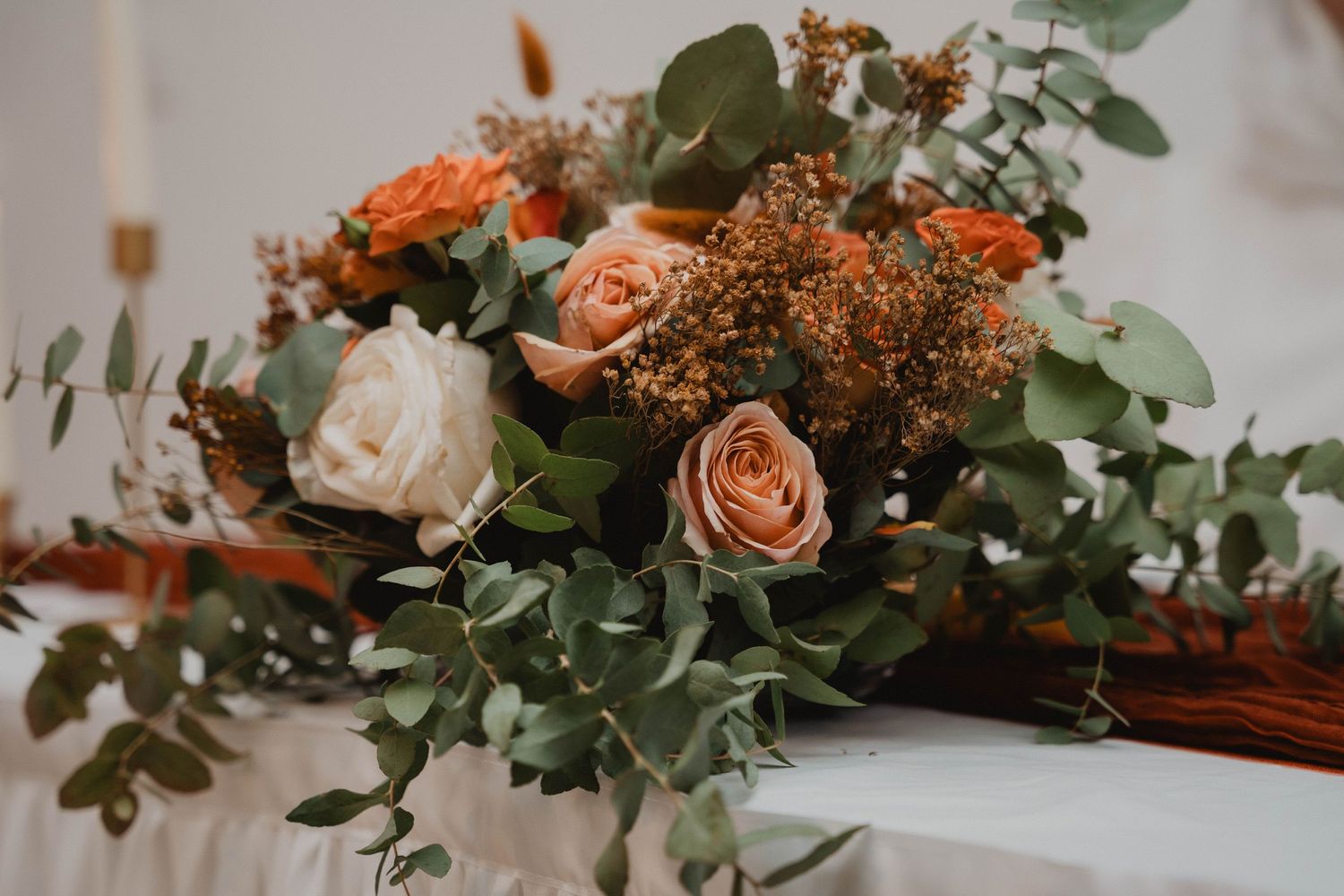 Élégante composition florale avec des roses couleur pêche et des feuilles d'eucalyptus pour la décoration de mariage.