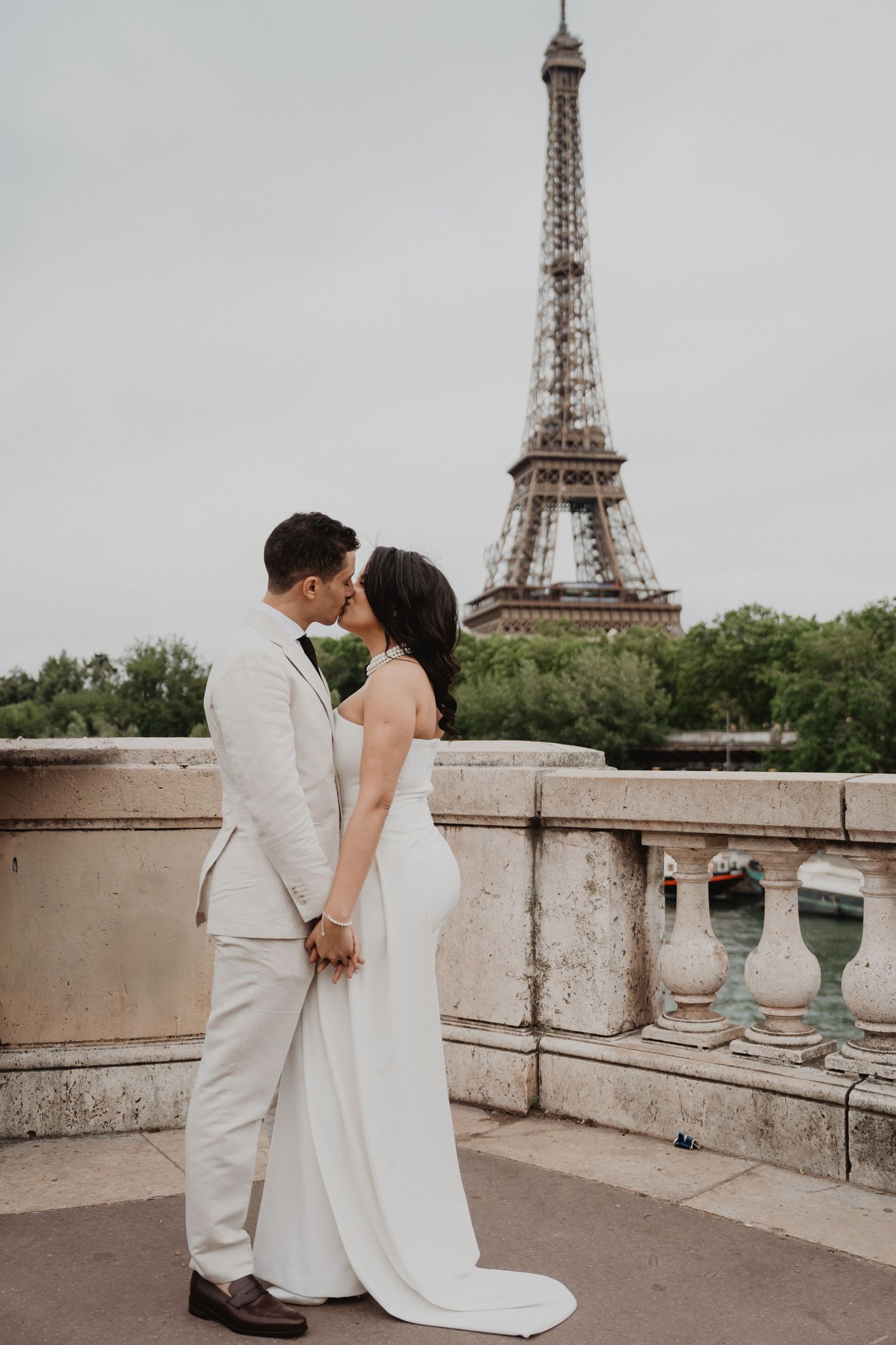 Romantic wedding photo with the Eiffel Tower in Paris as backdrop on an overcast day.