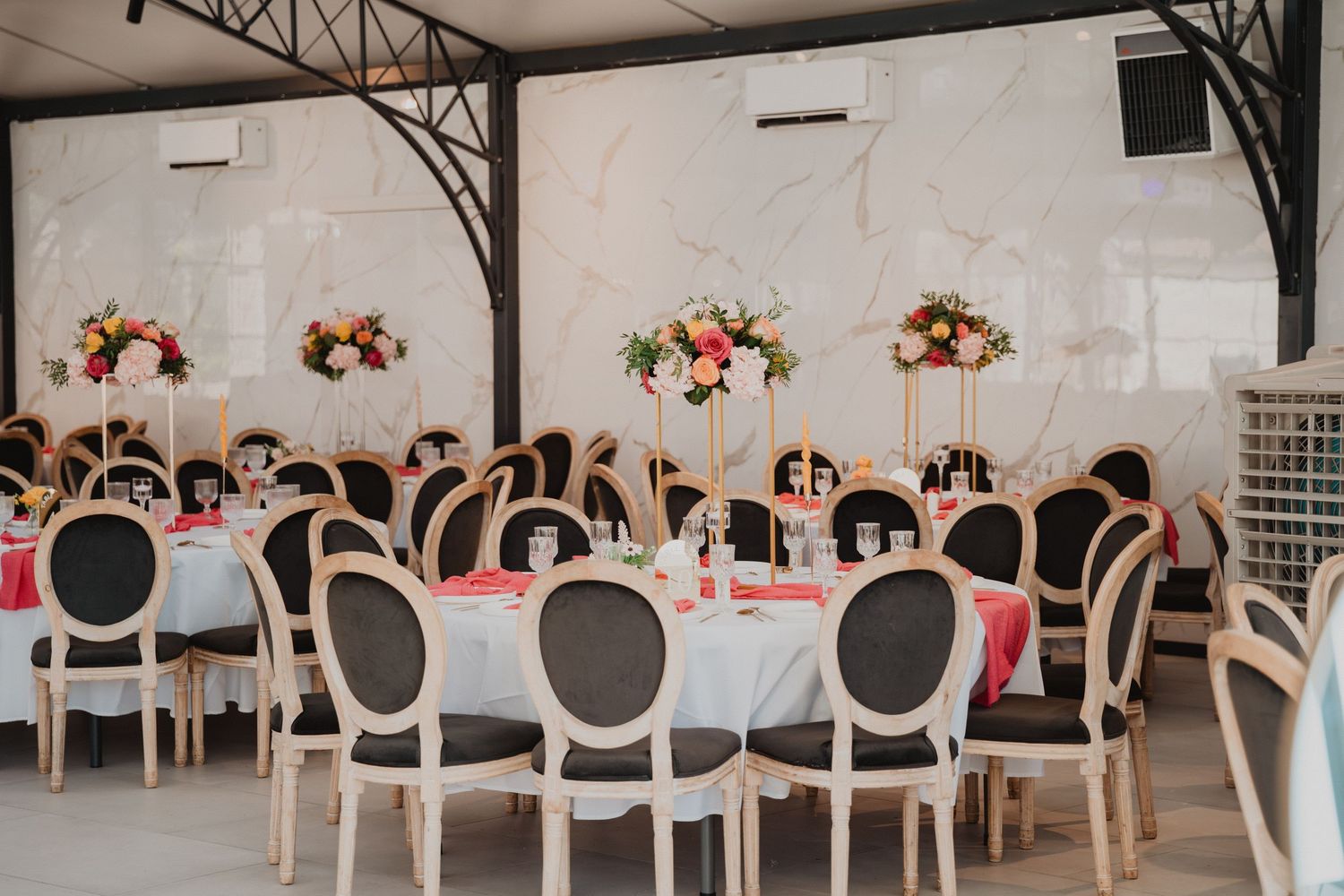 Une élégante décoration pour une réception de mariage, avec des chaises blanches et des centres de table floraux.