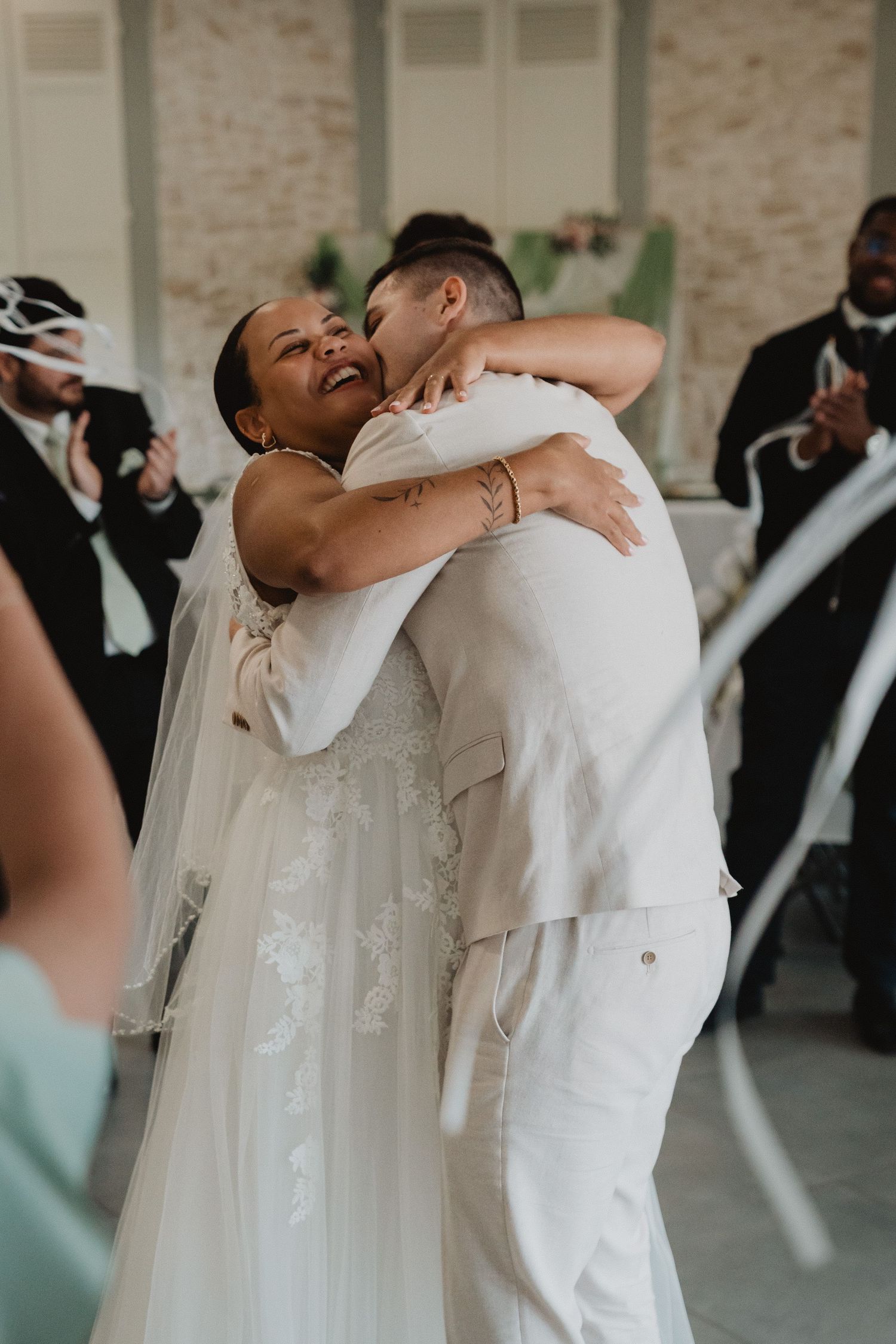 Célébration de mariage où les invités en tenue de soirée s'enlacent joyeusement.