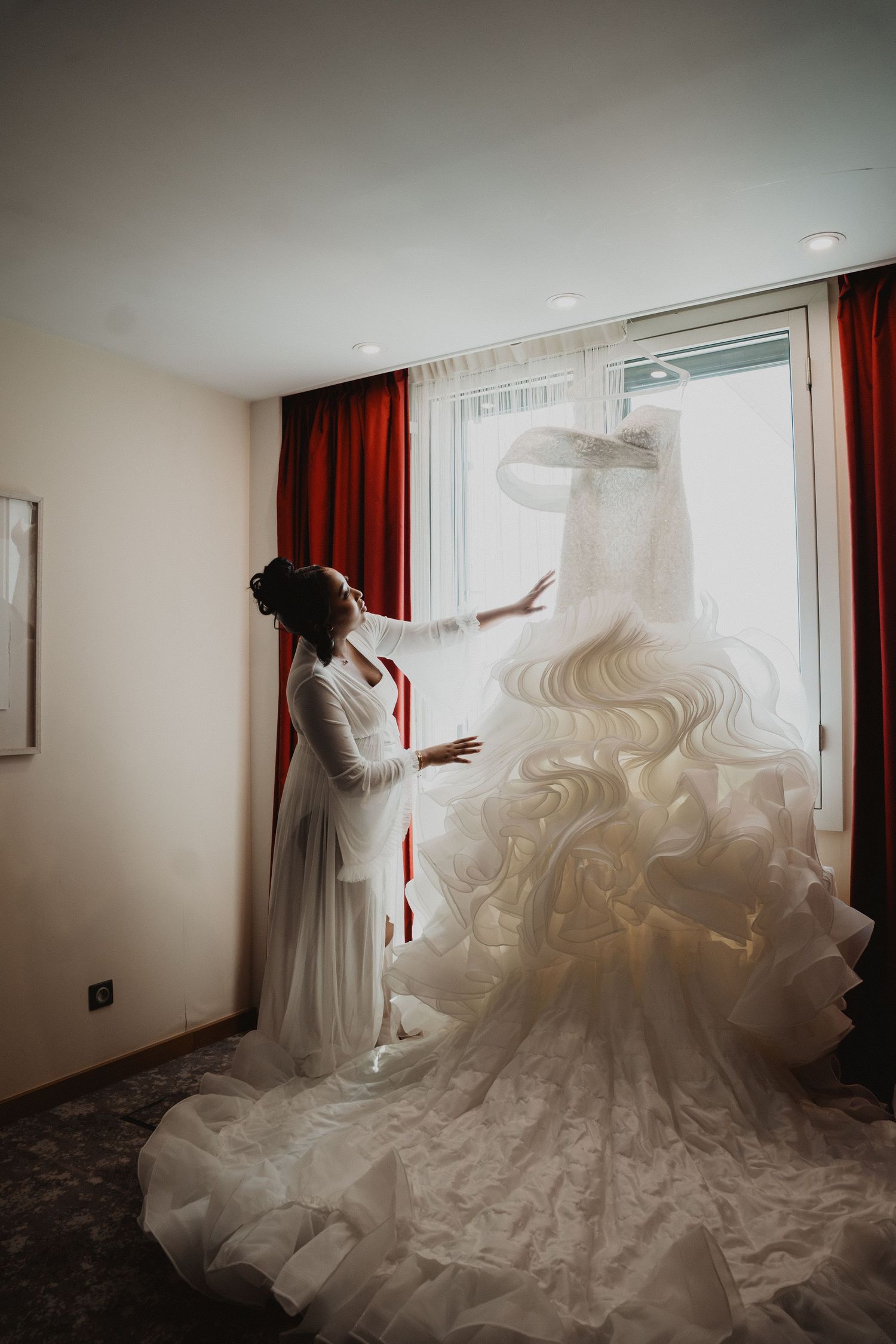 Séquence spectaculaire montrant une robe de mariée blanche et fluide disposée dans une chambre d'hôtel.