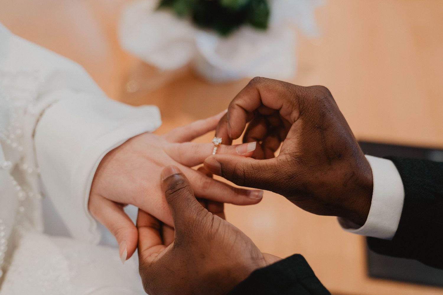 Close-up details of hands exchanging rings during wedding ceremony.