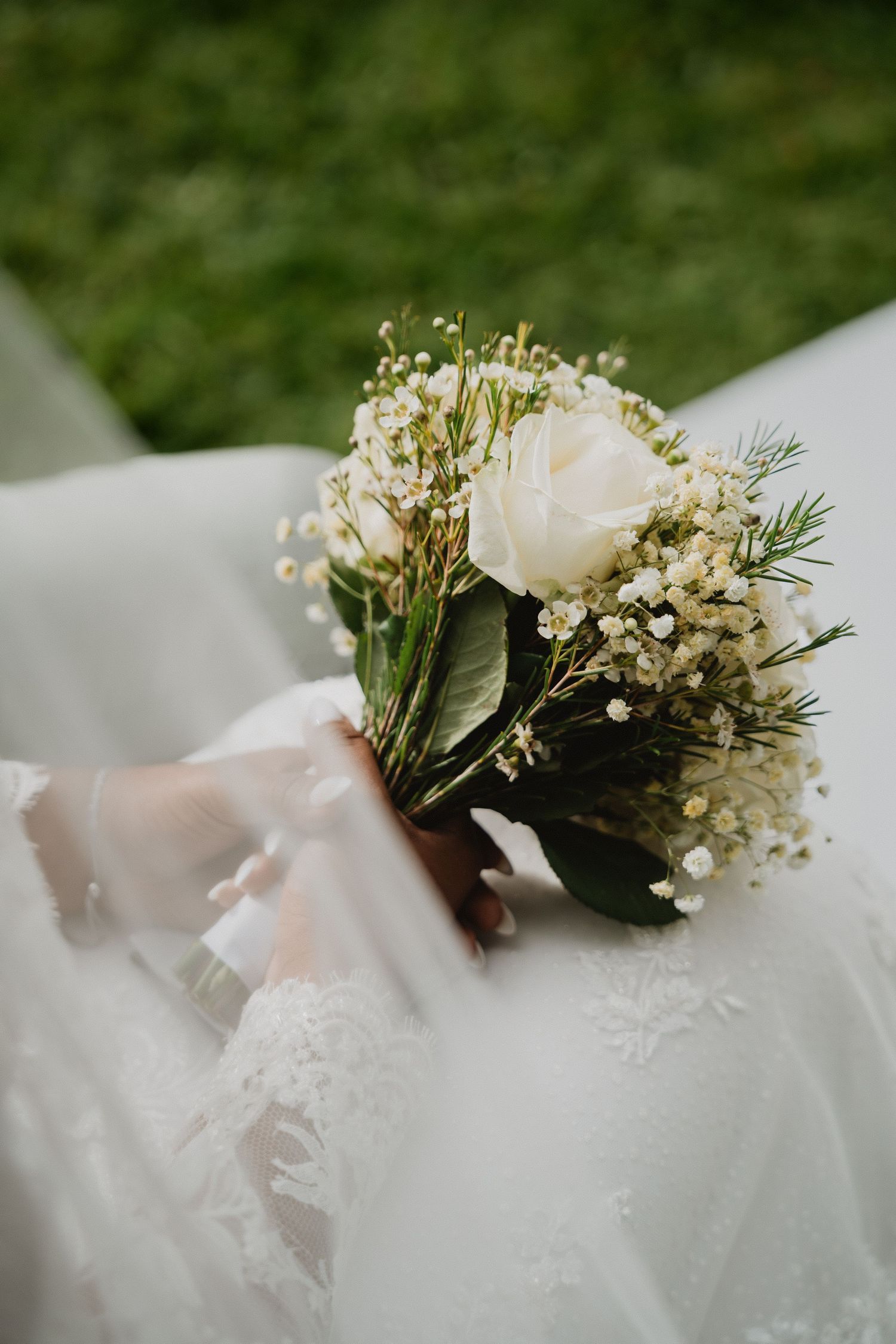 Boutonnière florale blanche délicate avec gypsophile et verdure sur un fond flou et doux.