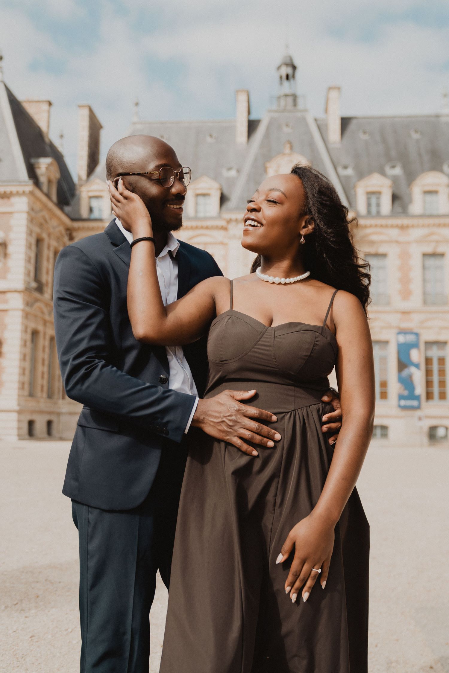 Un couple partage un moment intime devant l'architecture grandiose d'un château européen.