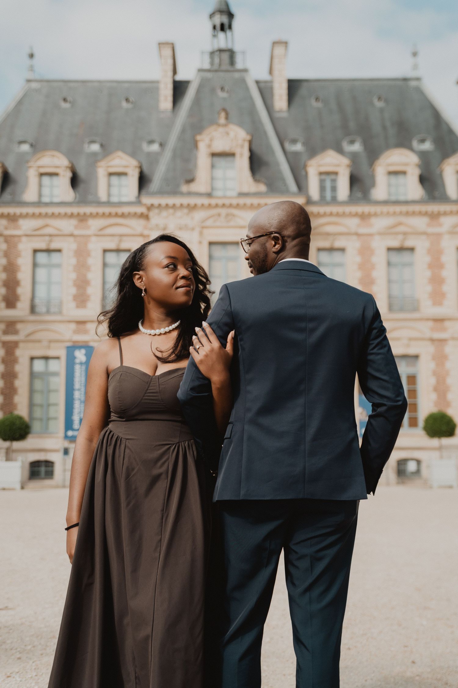 Un couple élégant pose devant un magnifique château français lors de leur séance photo de fiançailles.