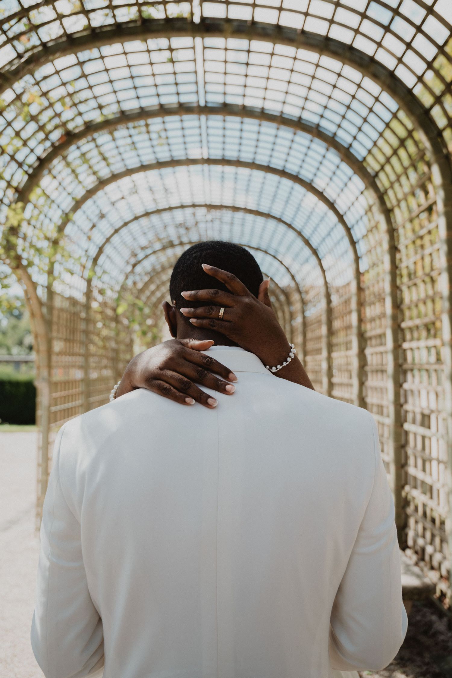 Romantic moment under a latticed garden pergola with natural lighting.