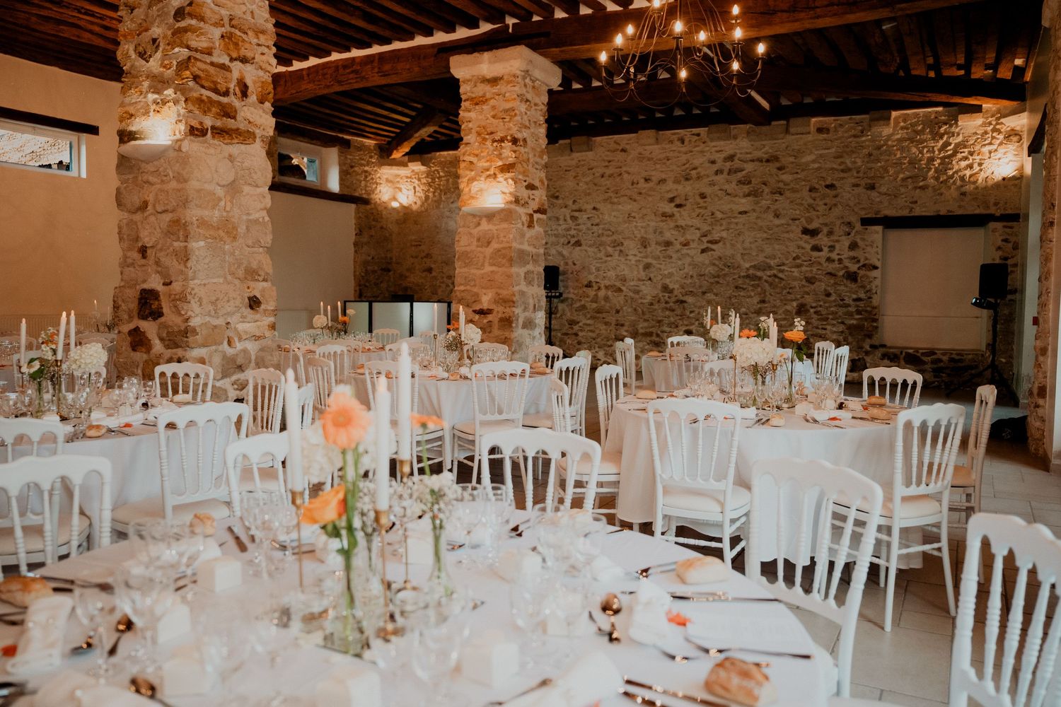 Lieu de réception de mariage rustique avec murs en briques apparentes et guirlandes lumineuses créant une ambiance chaleureuse.