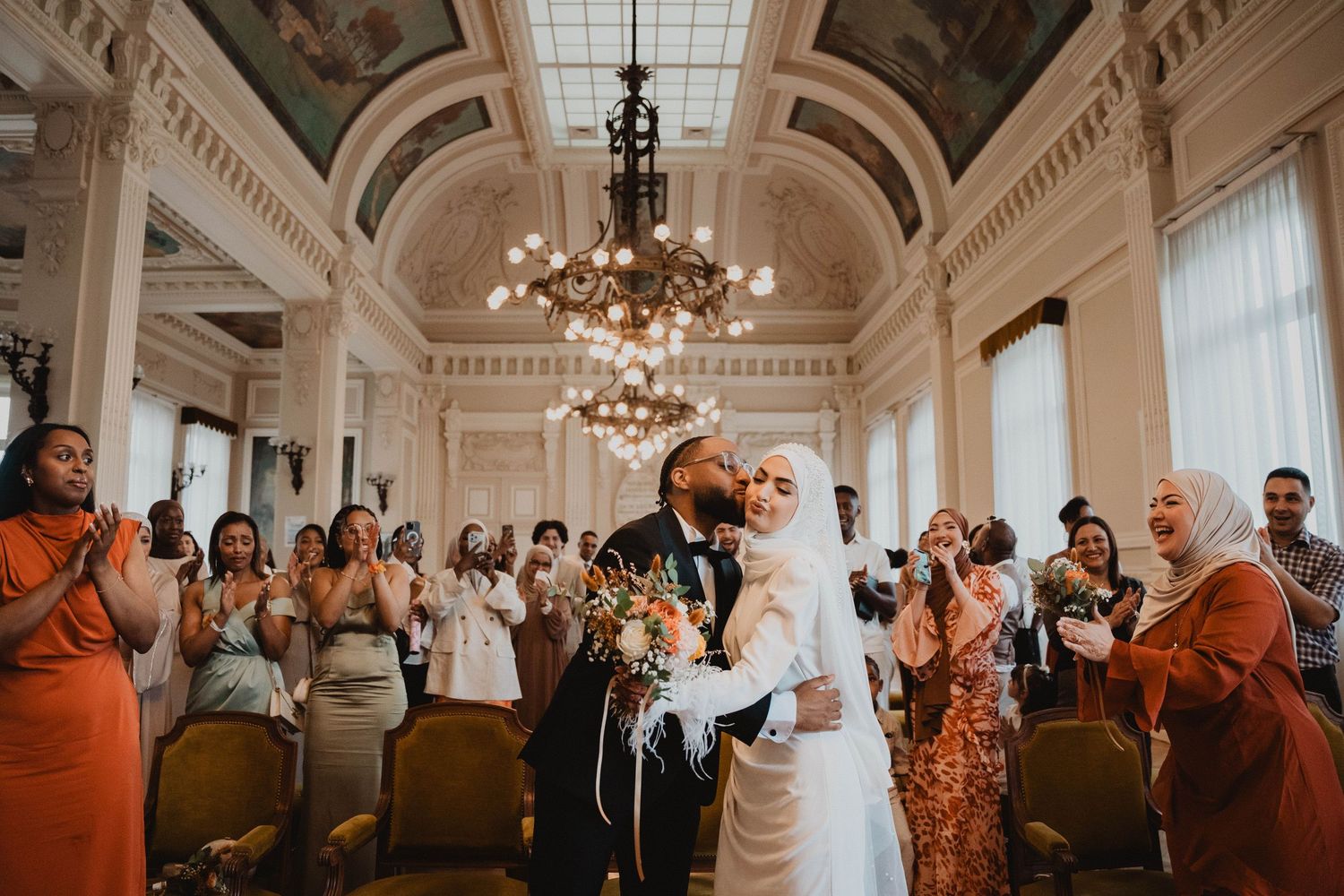 Cérémonie de mariage dans une grande salle aux plafonds voûtés et aux lustres ornés.