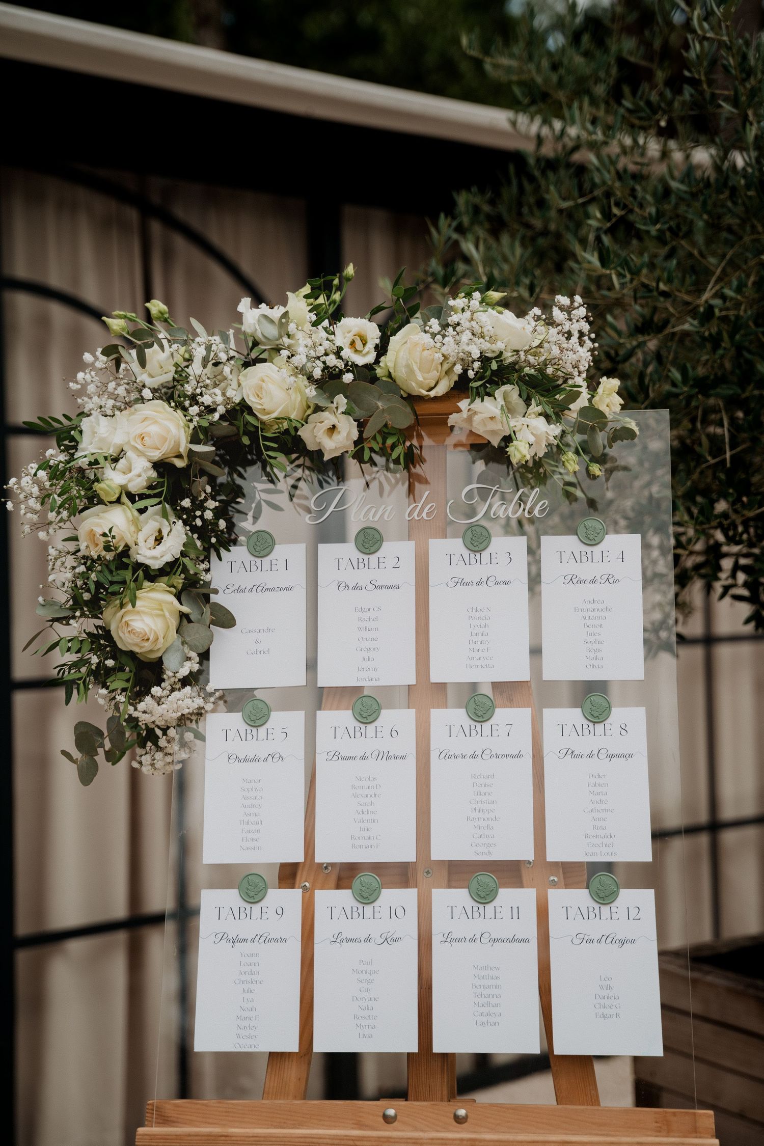 Élégant plan de table de mariage avec compositions florales blanches et marque-places imprimés sur supports en bois.