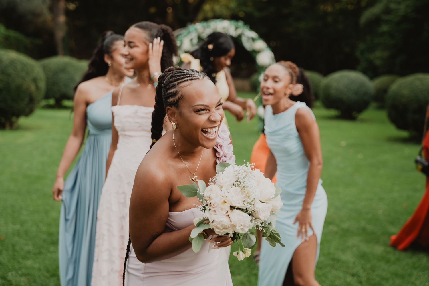 Les demoiselles d'honneur, vêtues de robes bleu clair, célèbrent un mariage sur une pelouse verte.