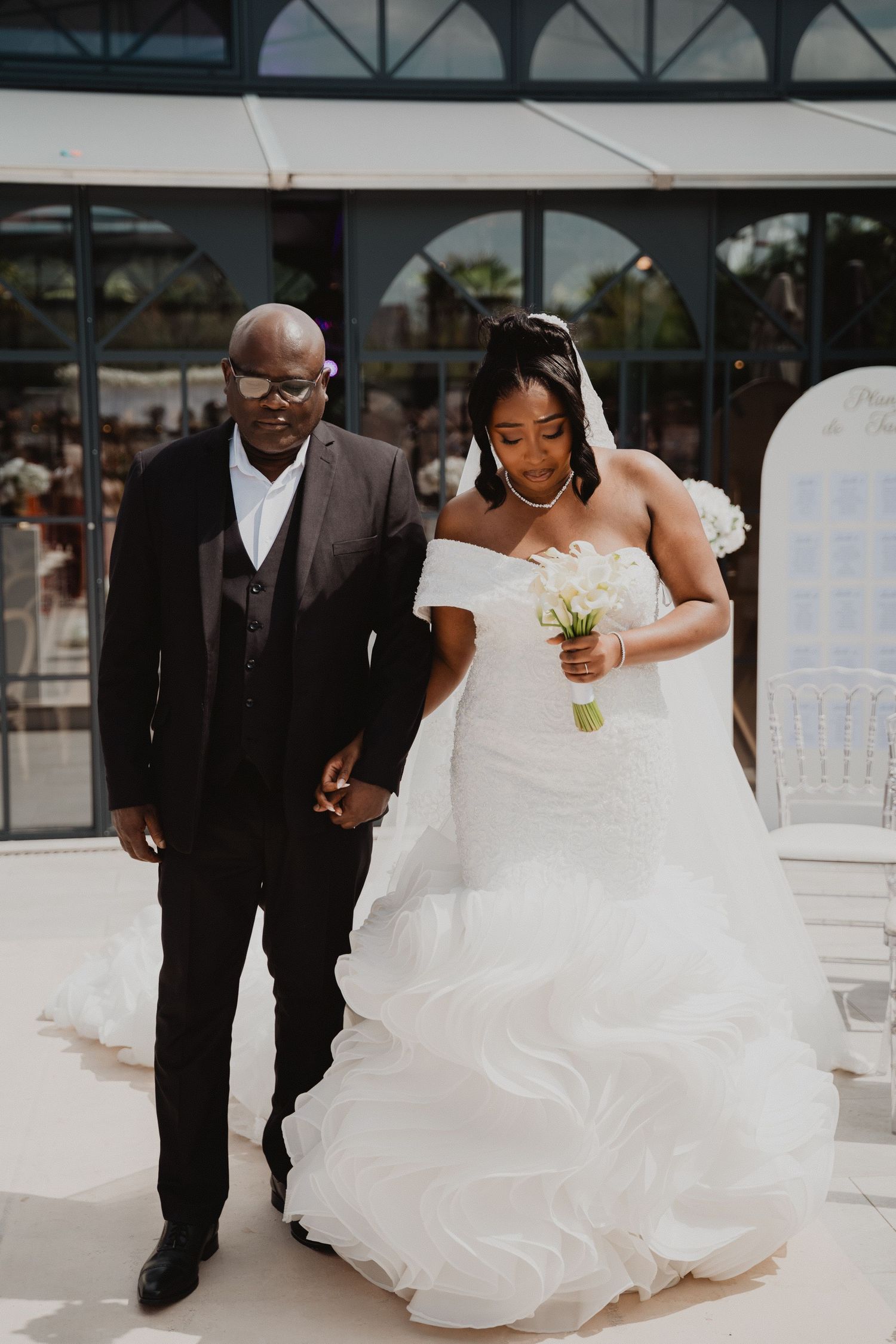 Un couple marchant ensemble lors de leur cérémonie de mariage, la mariée portant une robe blanche fluide.