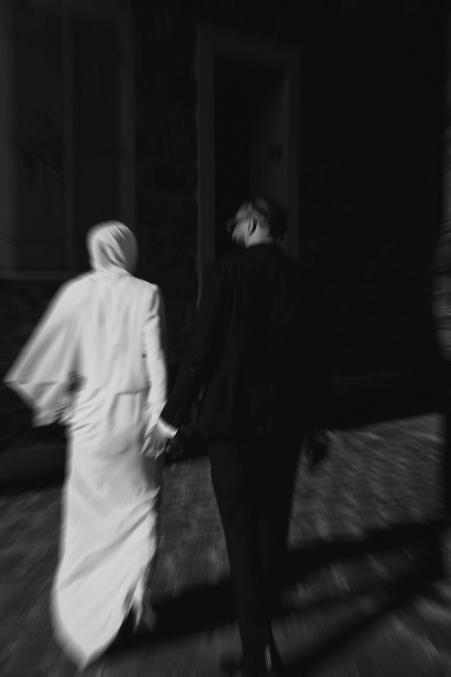 Artistic black and white motion blur of a figure in white moving through darkness.