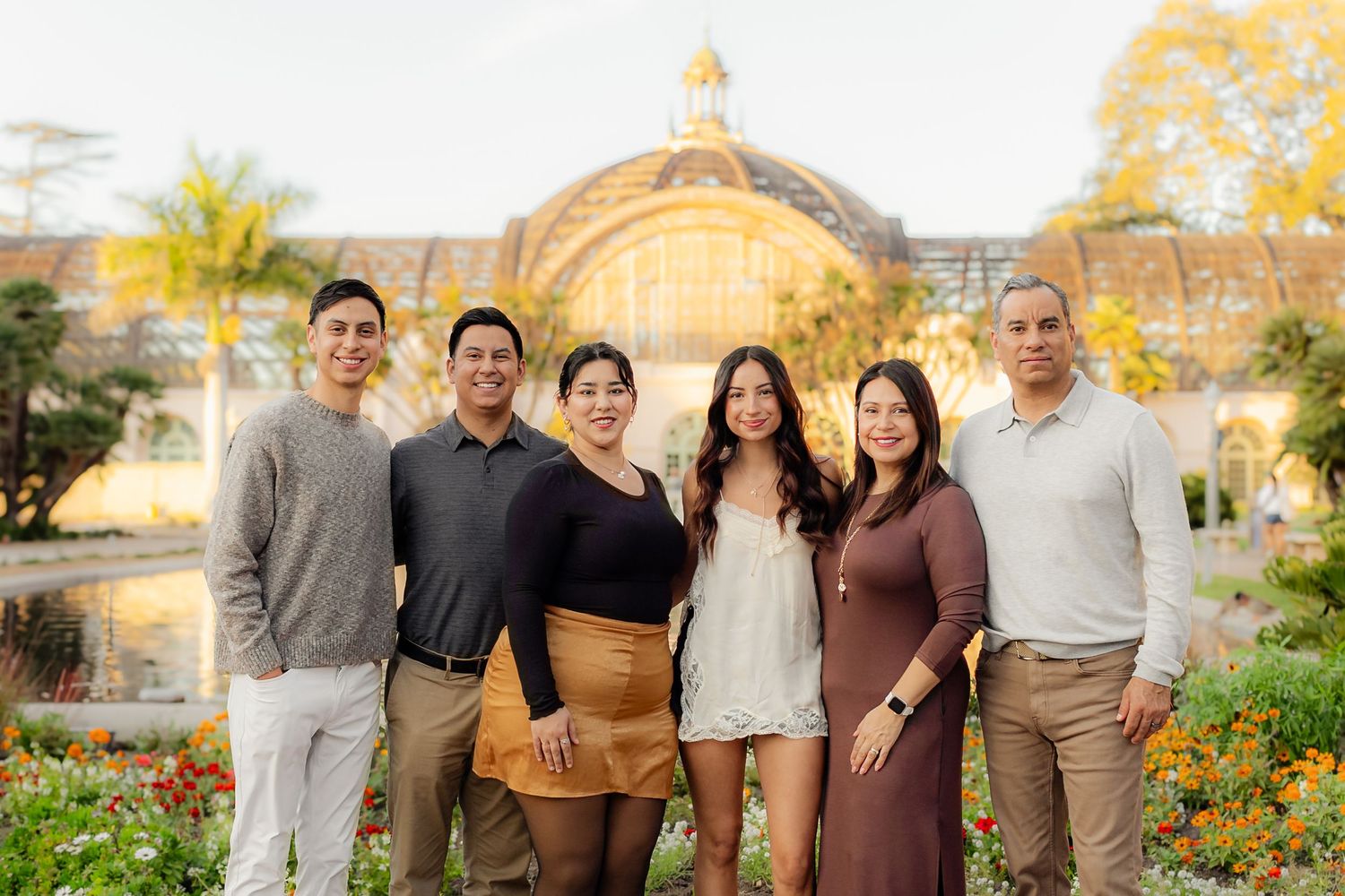 Extended family poses together in a garden setting during golden hour wearing coordinated earth-tone outfits.