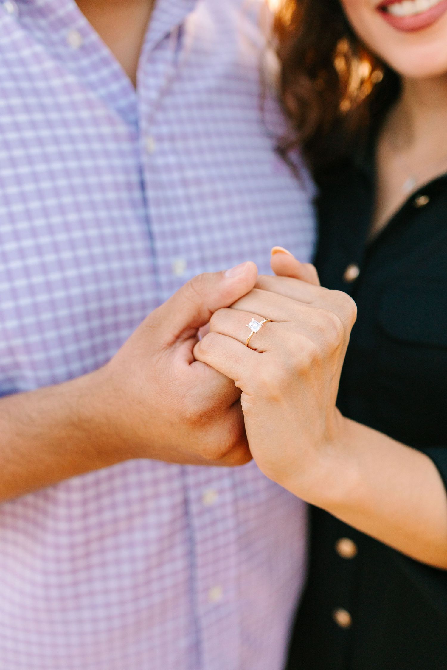 Close-up view of two hands clasping together with a gold engagement ring visible.