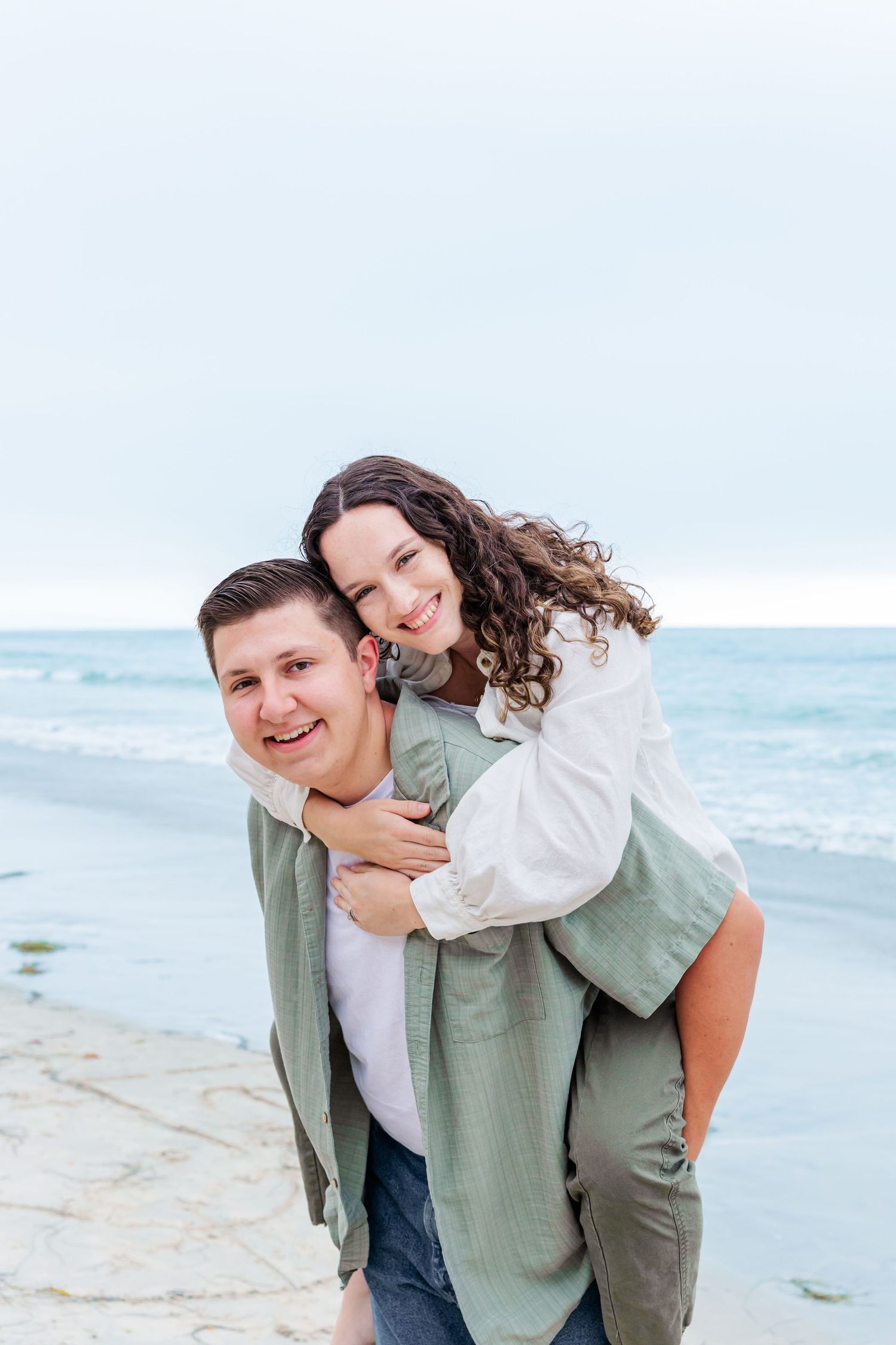 A piggyback ride on the beach captures a joyful moment between two people.