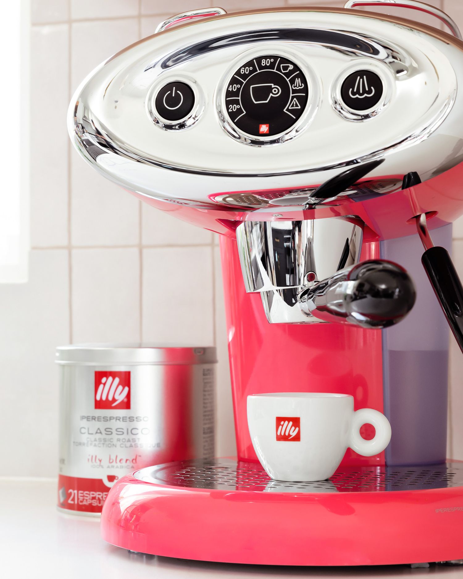 Red illy espresso machine with silver details and coffee tin displayed on counter.