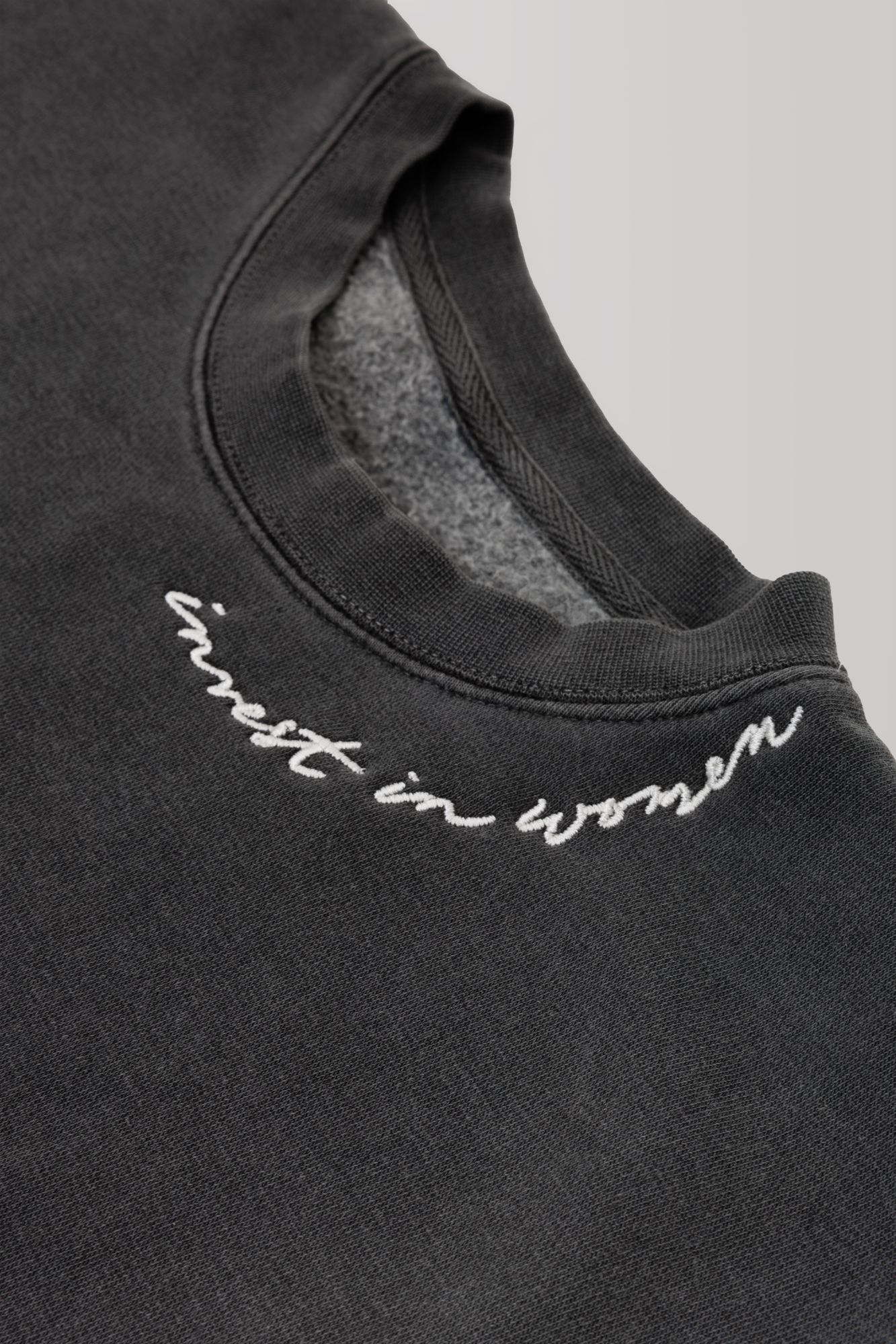 Close-up of dark sweatshirt neckline with cursive embroidered text.