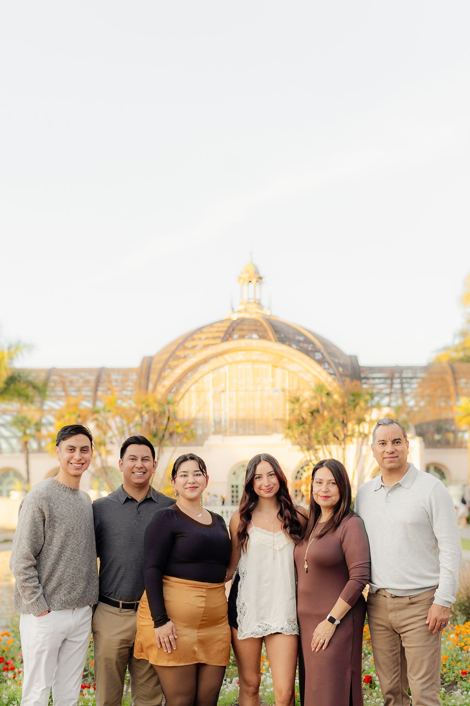A group poses together in front of an ornate domed building during golden hour.