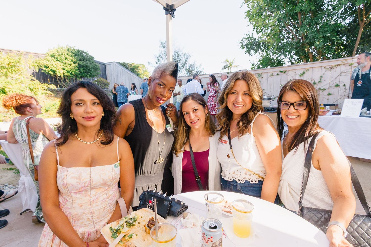 Friends gathered at a casual outdoor party with drinks and smiles.