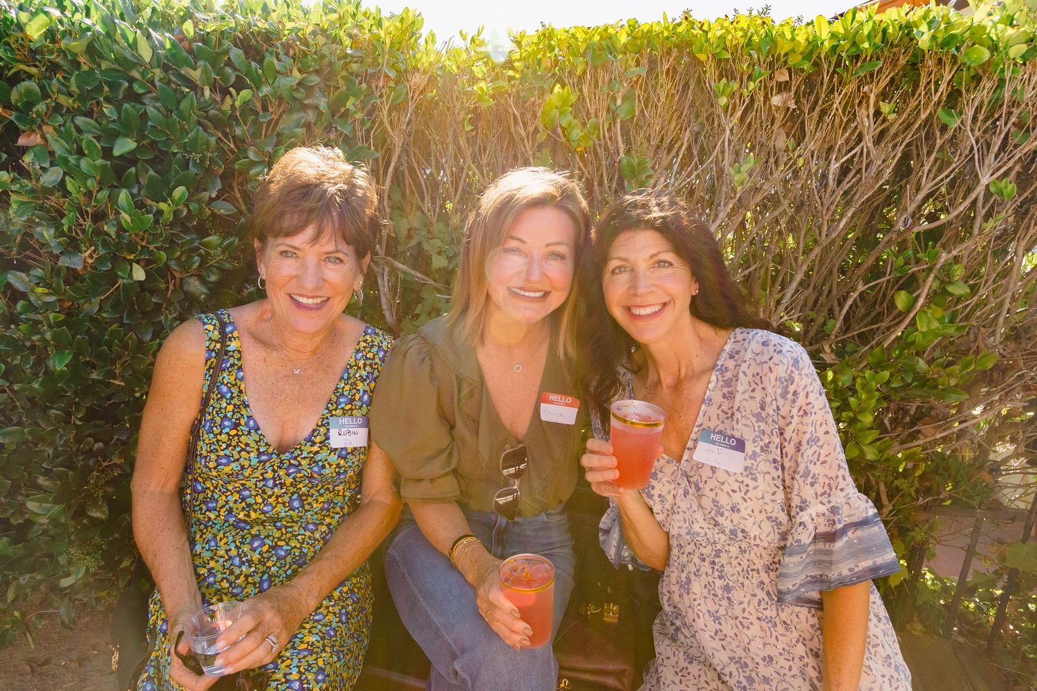 Friends enjoying drinks and conversation in a lush garden setting during golden hour.