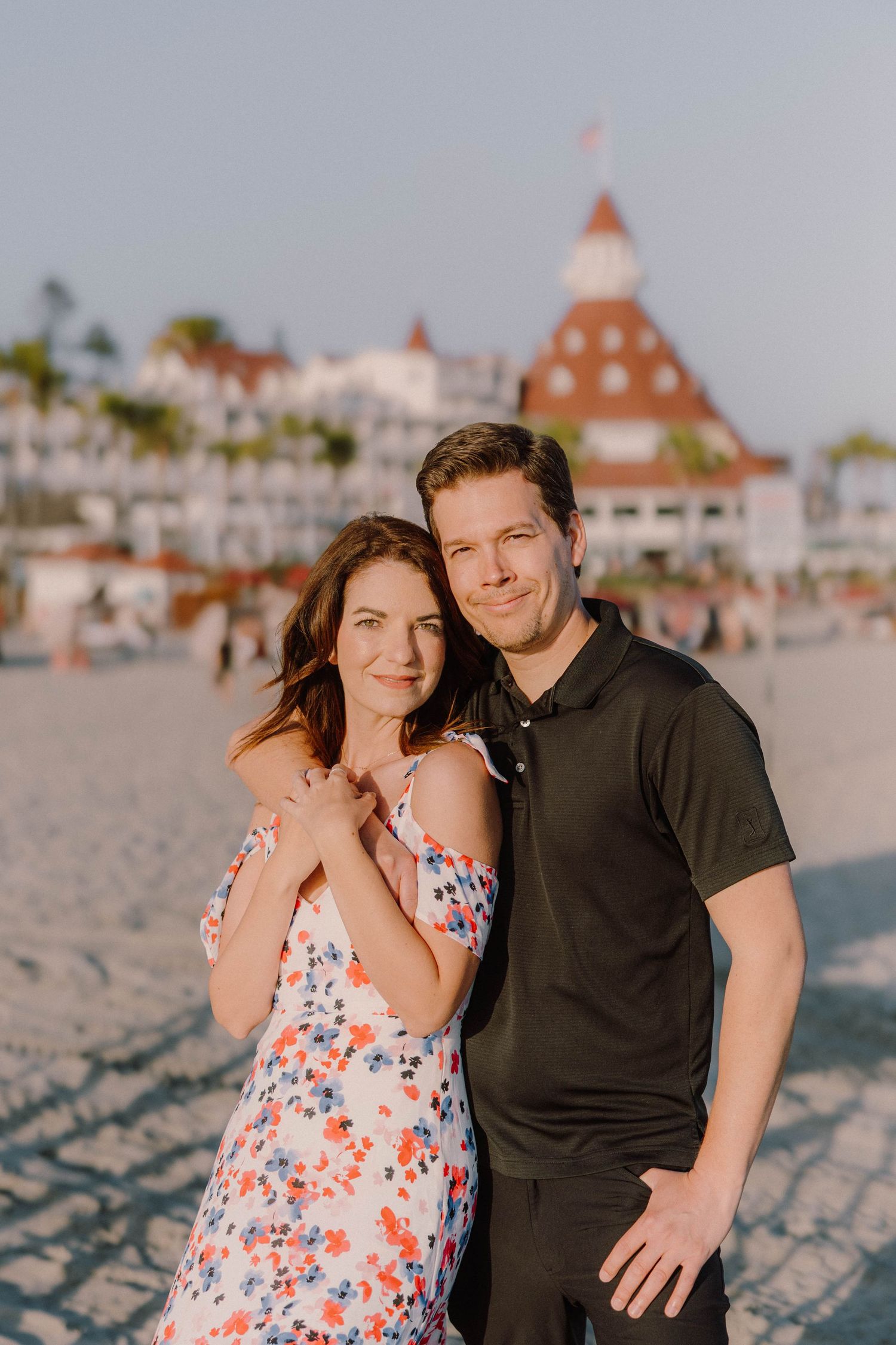 Affectionate beach portrait with Hotel del Coronado's distinctive architecture in background.