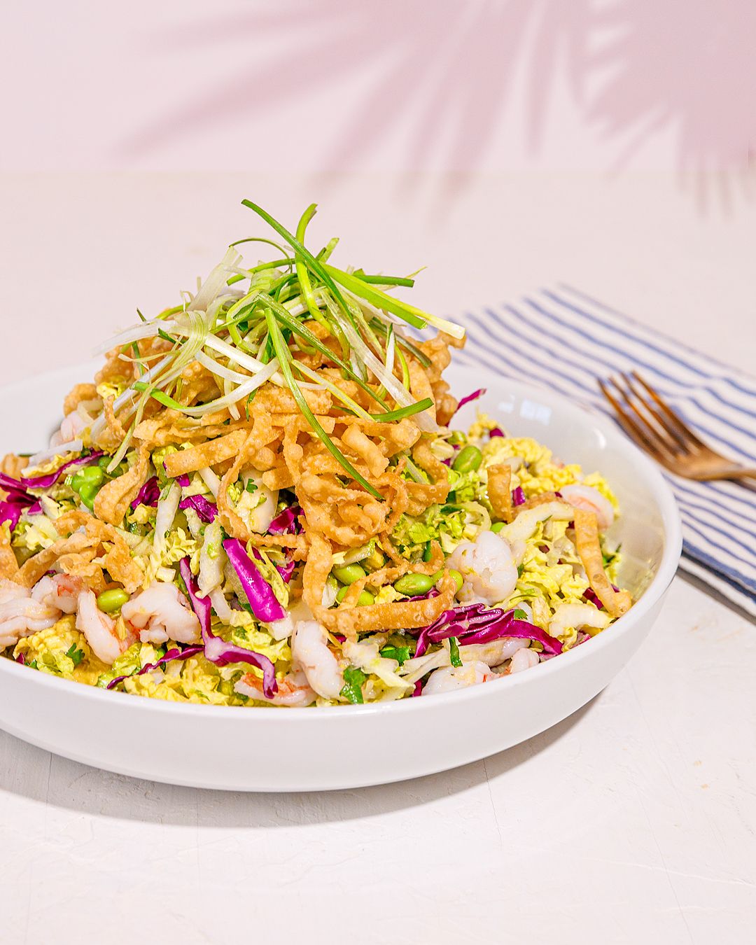 Asian-inspired coleslaw with shredded cabbage, carrots and crispy toppings on white plates.