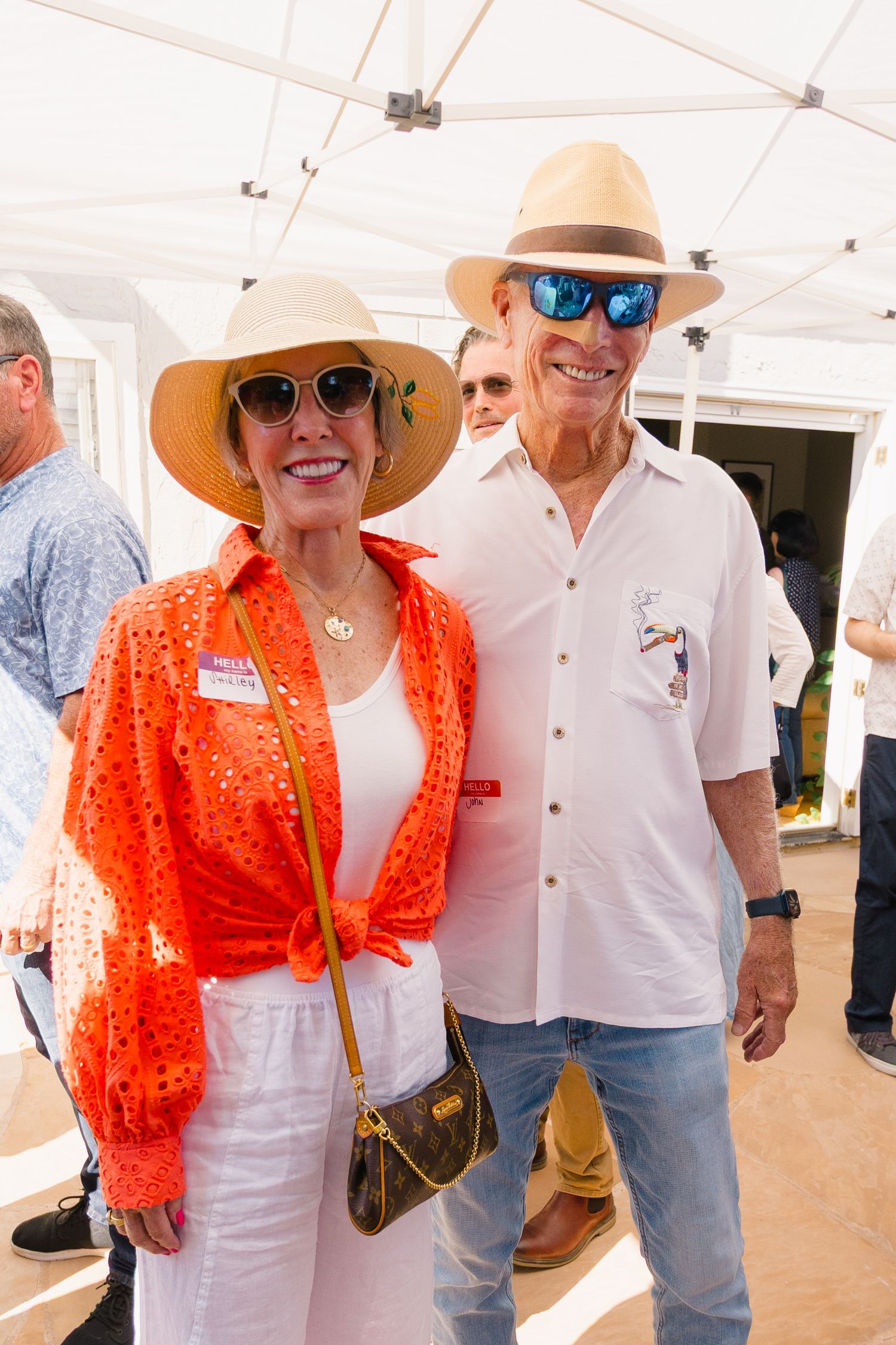 Guests in summer attire enjoying a casual outdoor event under a white tent.