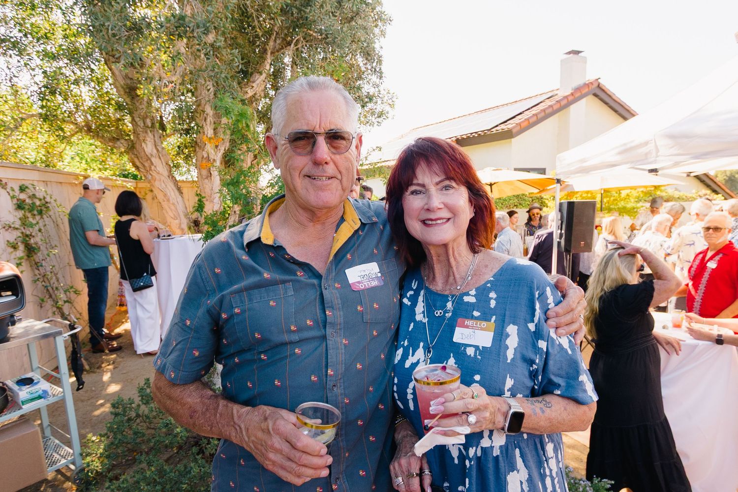 Casual outdoor party scene with guests wearing sunglasses and summer attire.