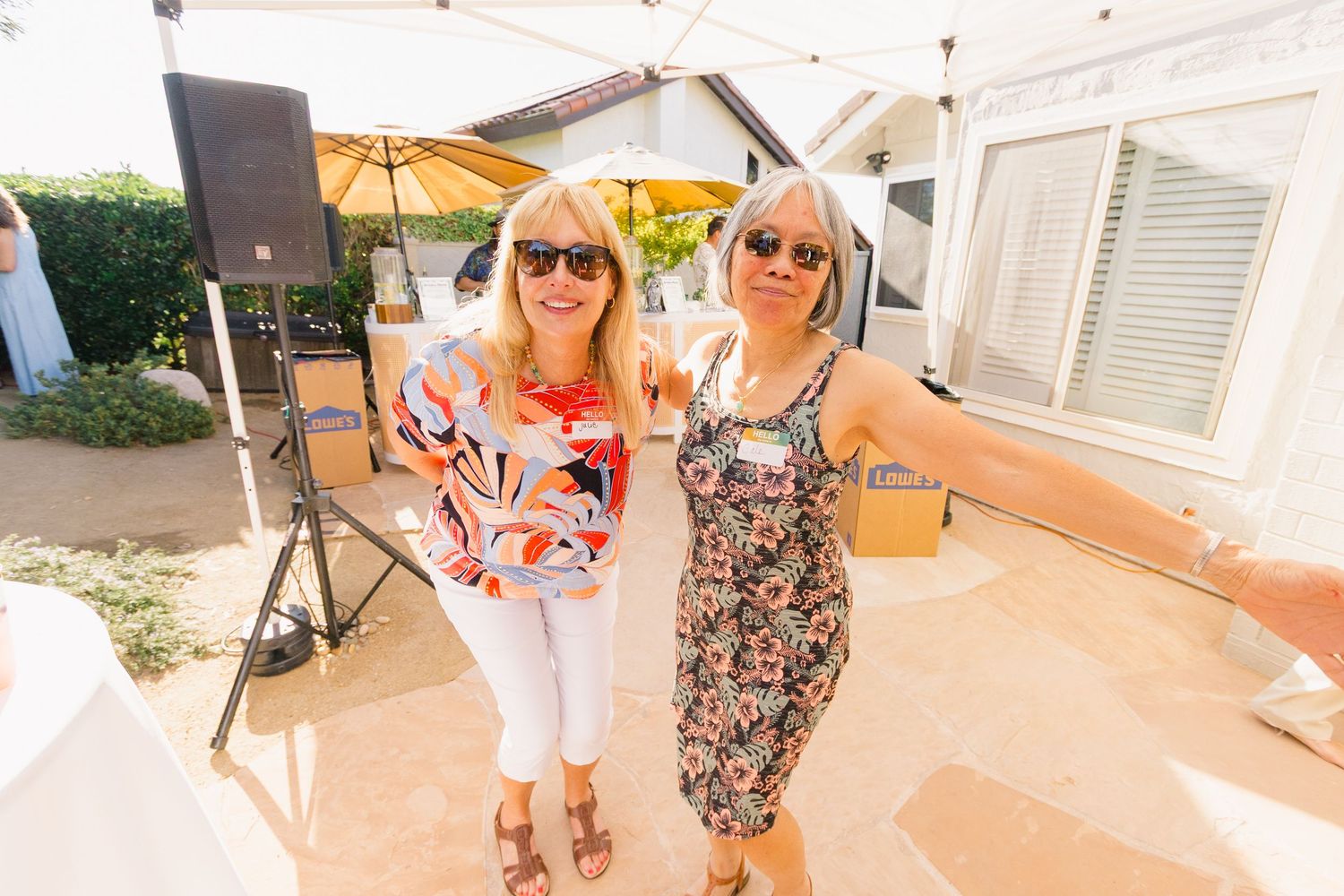 People socializing at an outdoor party with white tents and floral decorations.