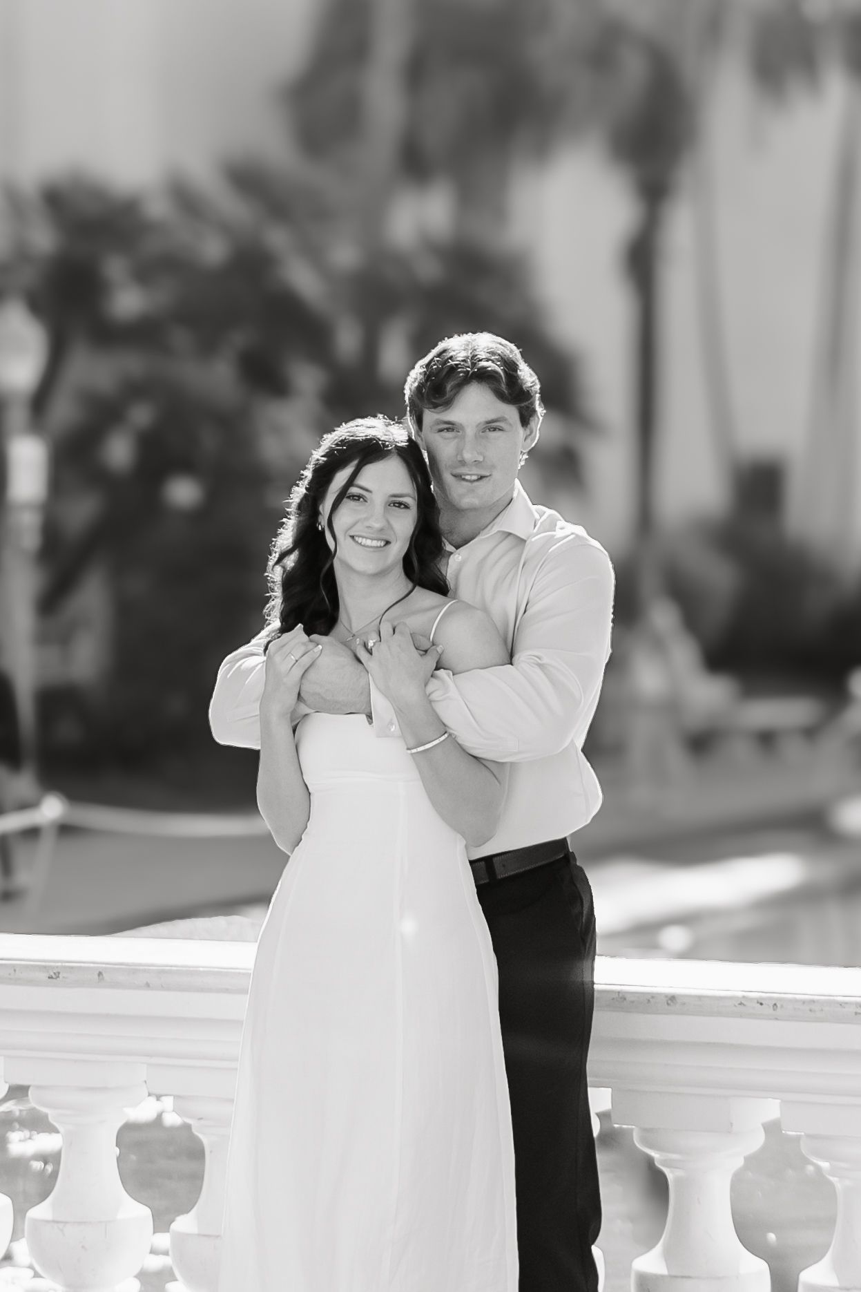 A romantic black and white photo sequence of a couple dancing together on a balcony with white railings.