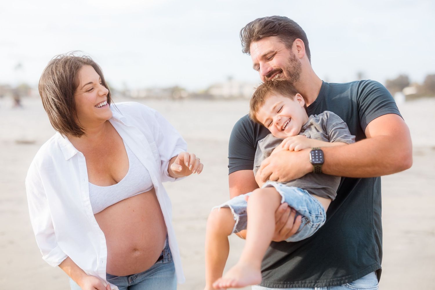 Loving couple shares tender moments during a casual beach photoshoot.