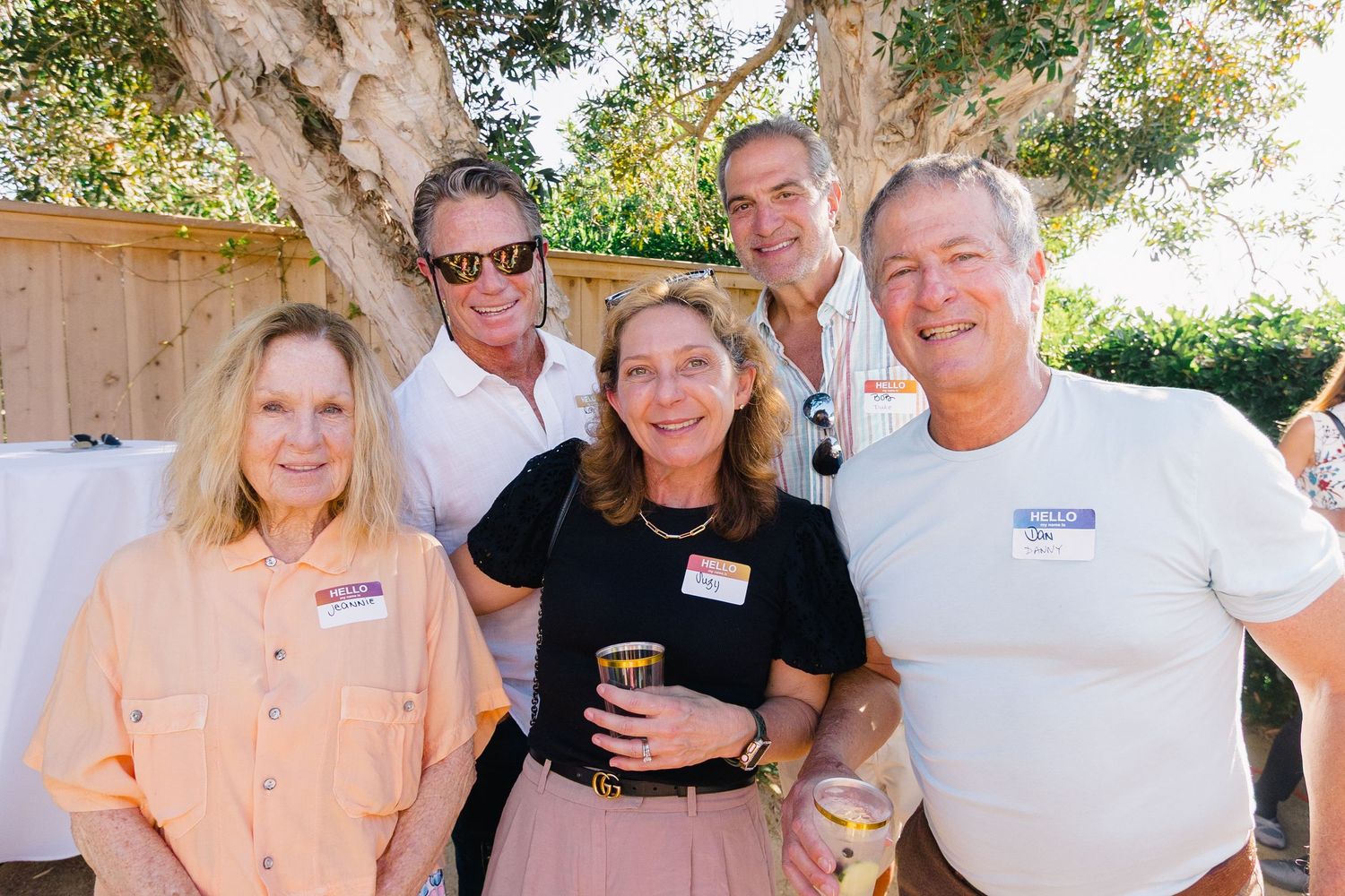 Friends gathering and socializing at a sunny outdoor party under trees.
