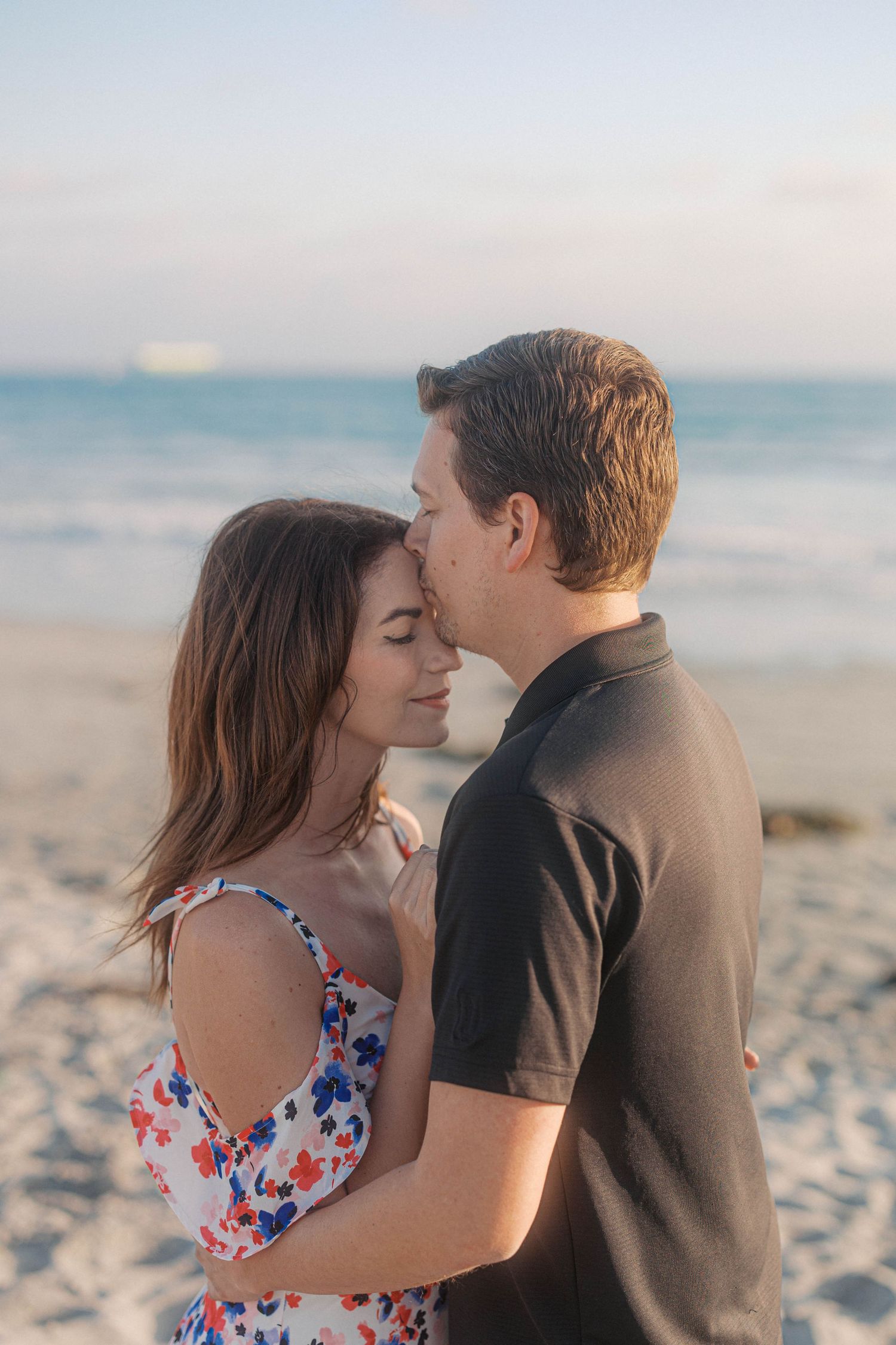 An intimate moment between a couple on a sandy beach at dusk.